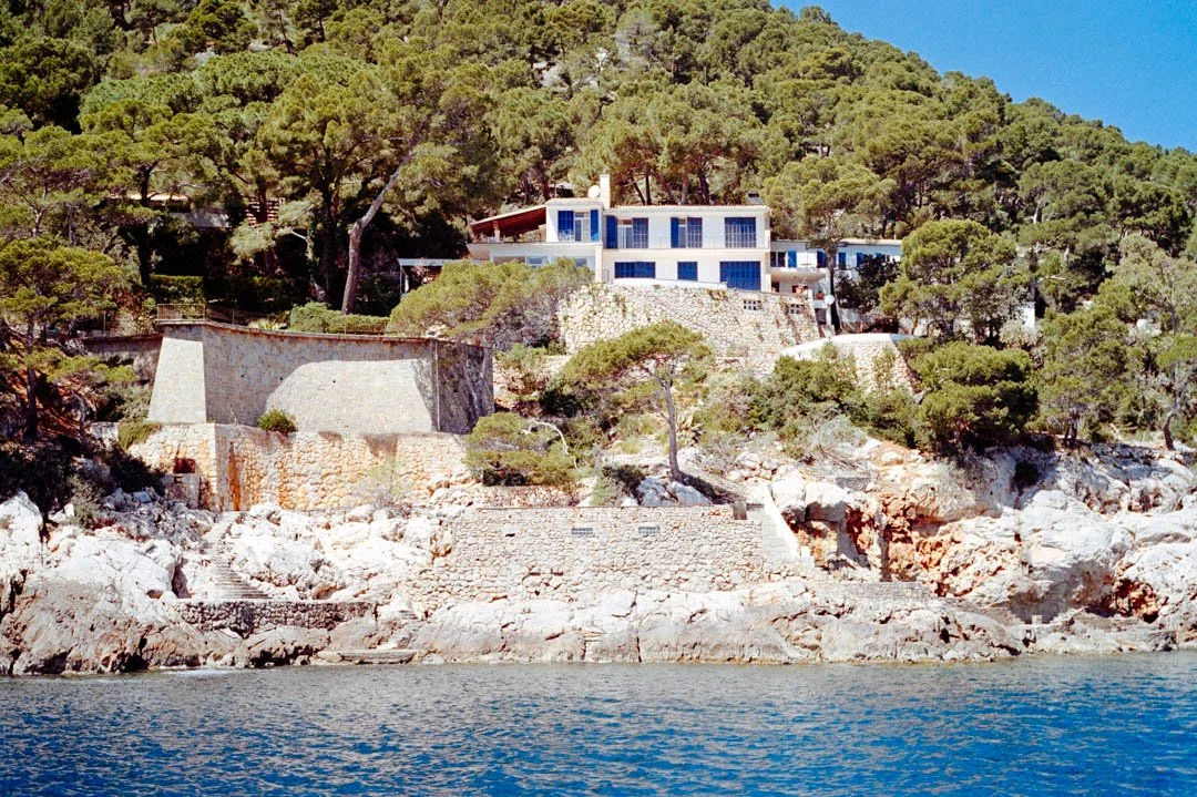 house on cliff face near blue ocean, Formentor beach Majorca
