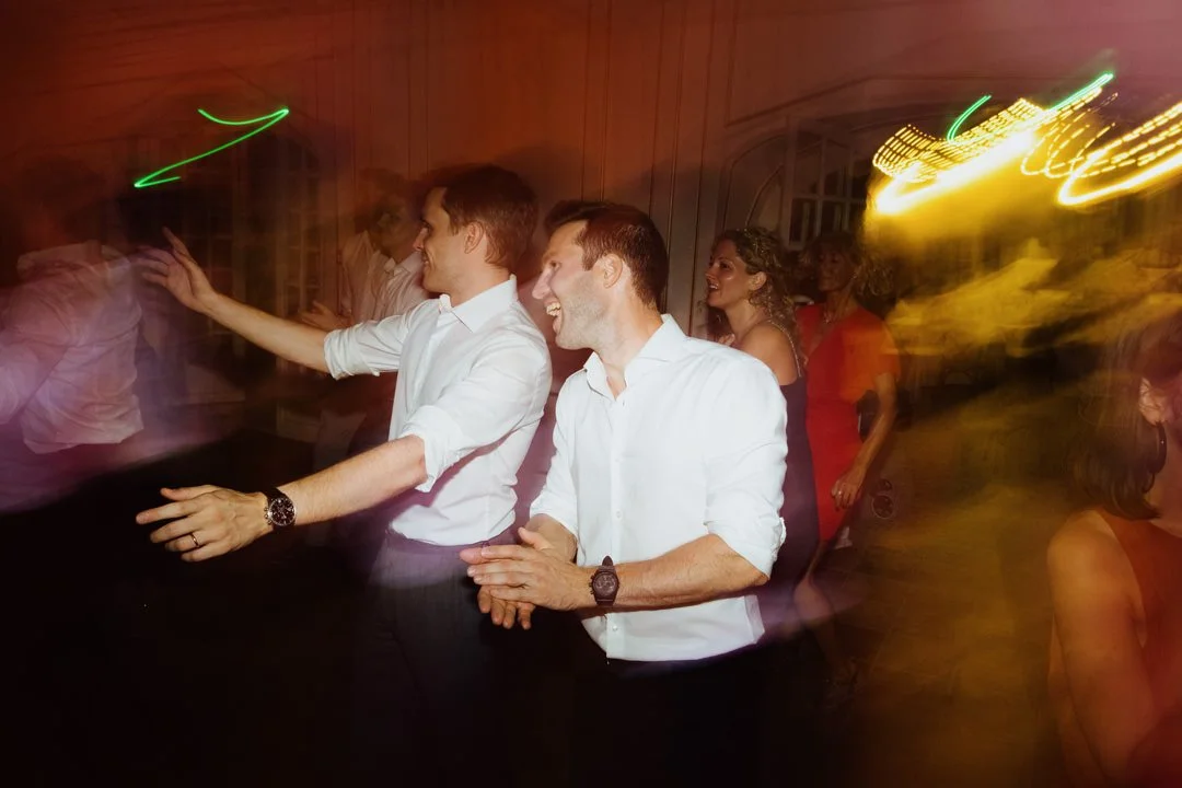 People dancing and socializing at a party with colorful lights.