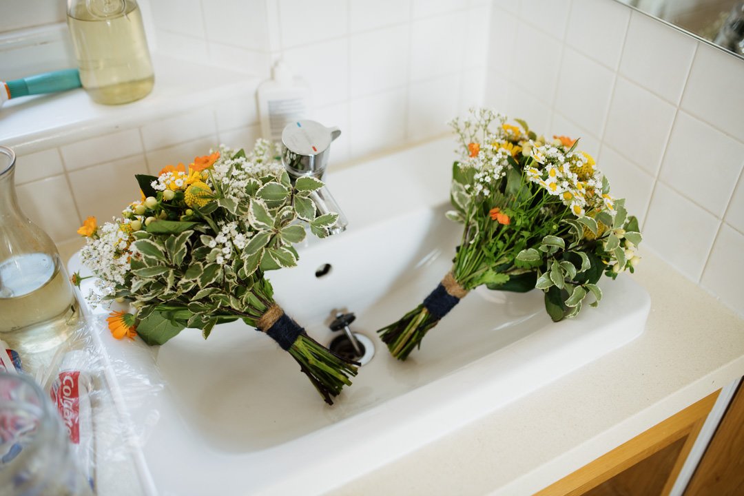 orange and yellow wedding flowers laid in sink