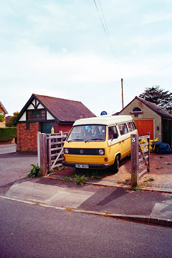 yellow t25 camera van on driveway near wooden gate, canon a-1