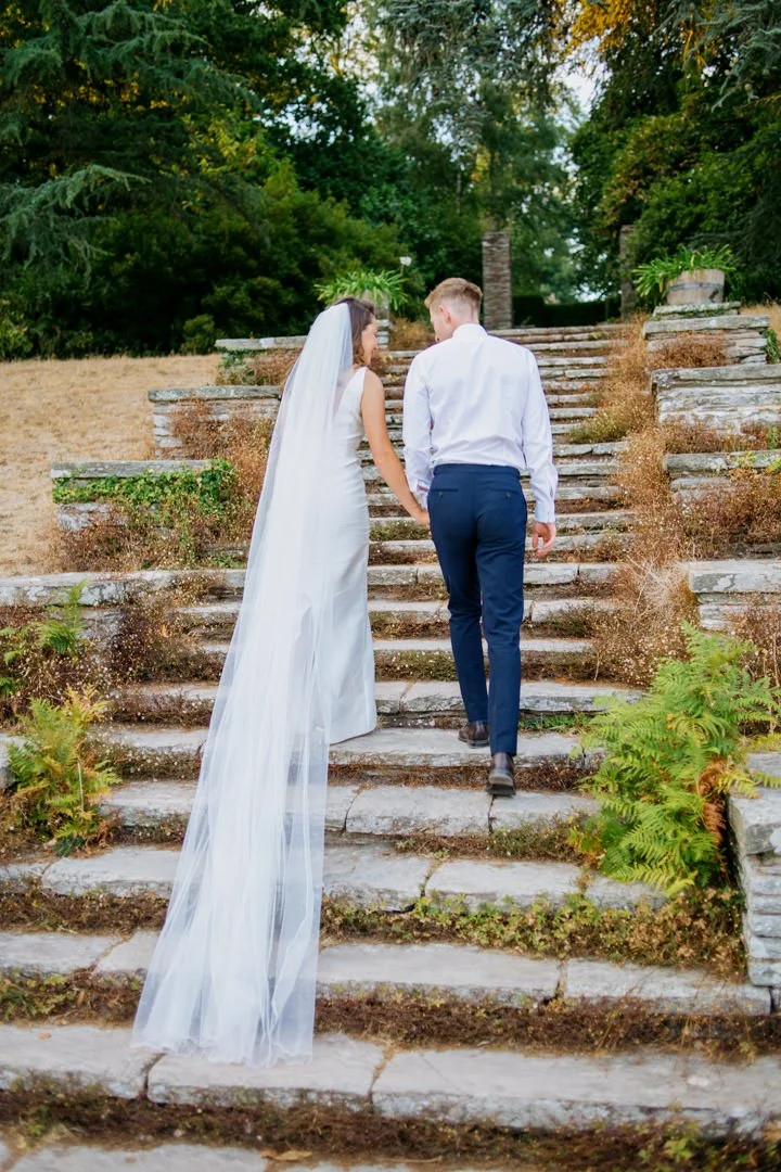 bride and groom climbing stone steps in garden, hestercombe house wedding venue