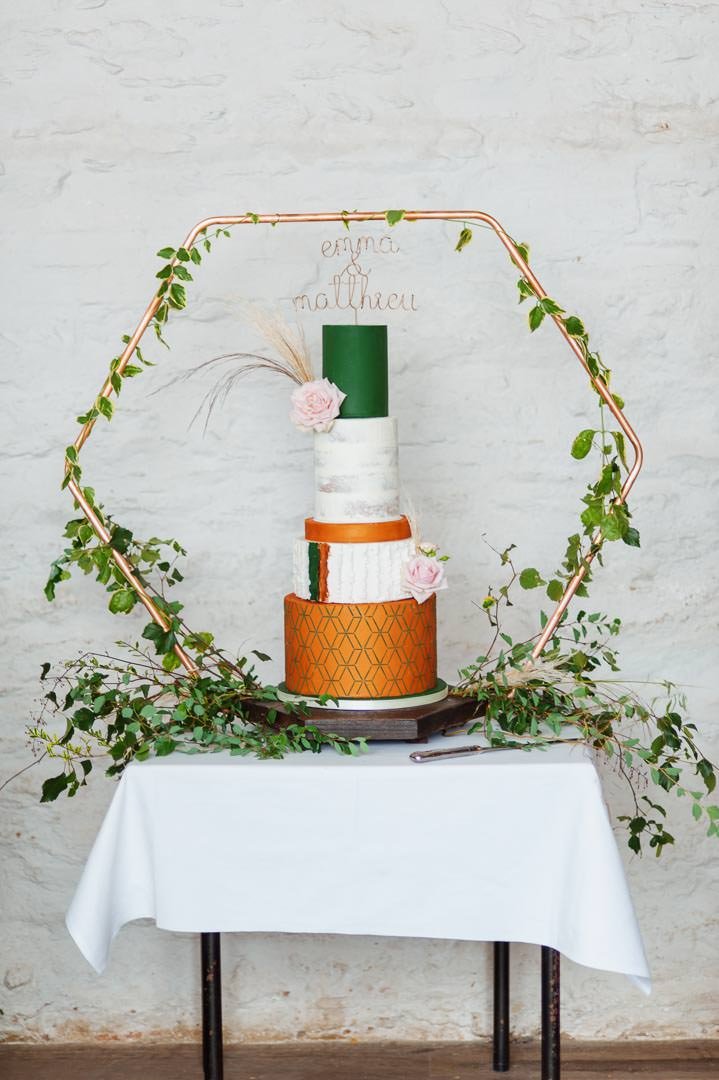 wedding cake with green and orange icing and hexagonal frame