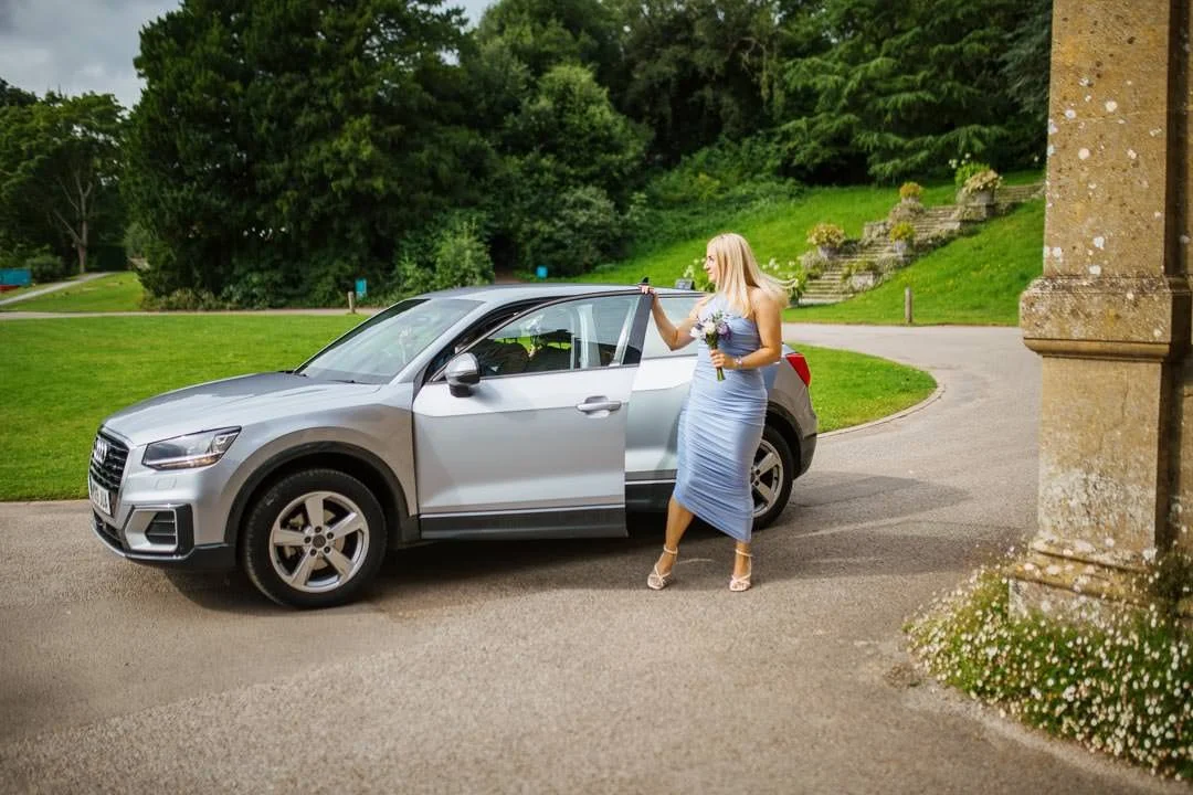 bridesmaid getting out of grey car holding flowers, Hestercombe House taunton