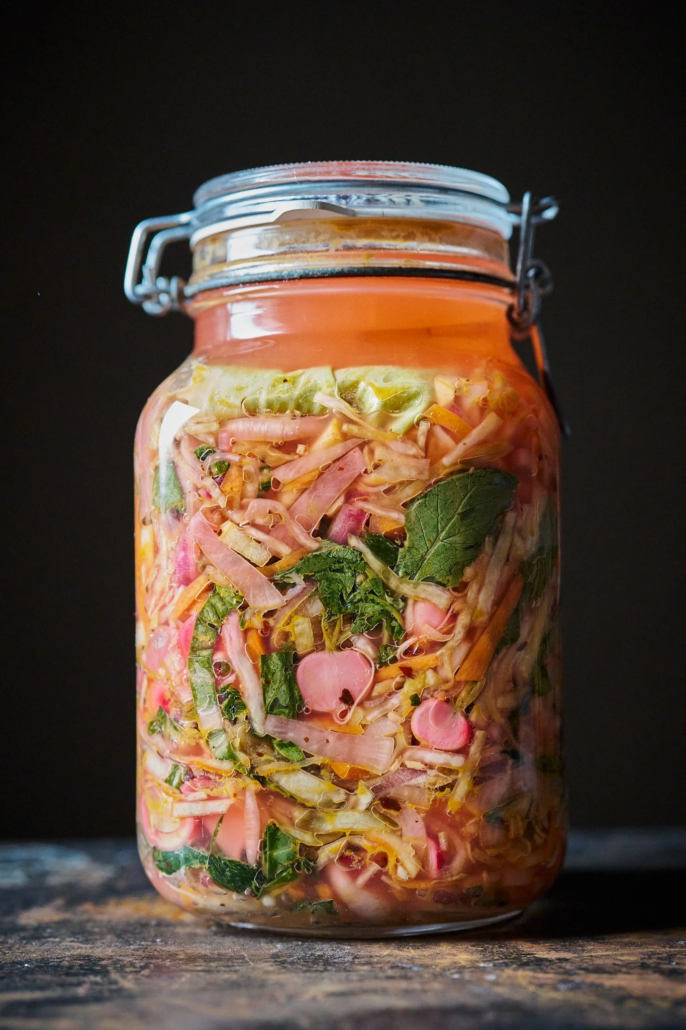 Ein Glas mit essigem saurem Sauerkraut mit Karotten, Radieschen und Kräutern darin