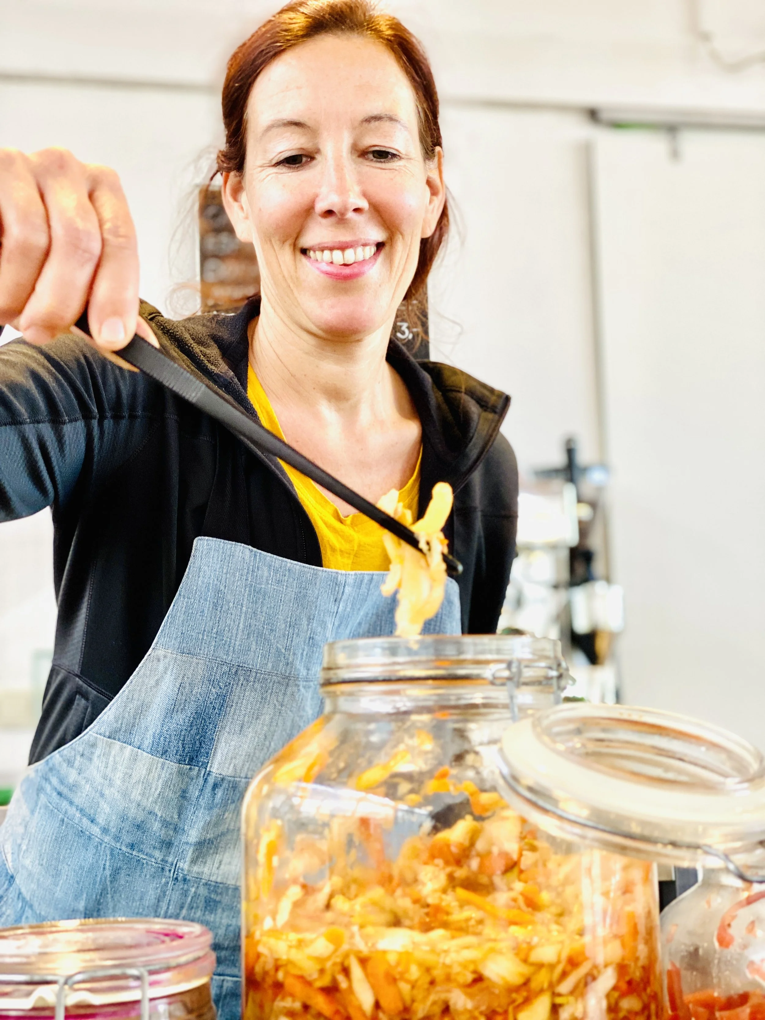 Eine lachende Frau beim Essen von selbstgemachtem Kimchi in einer Küche.
