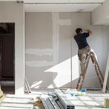 Ragazzo su scala che rifinisce muro in cartongesso