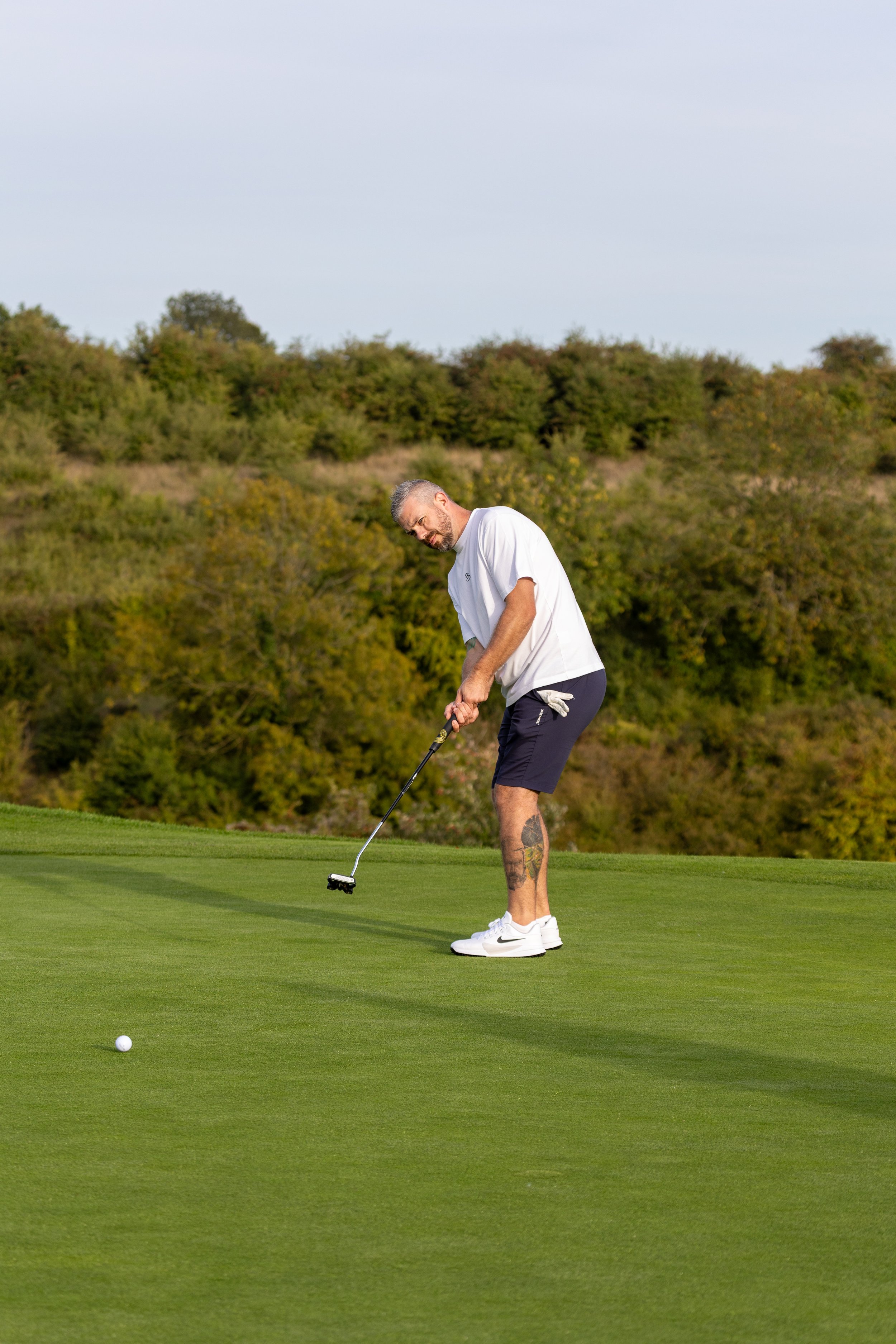 A man on a golf course preparing to hit a golf ball on the green.