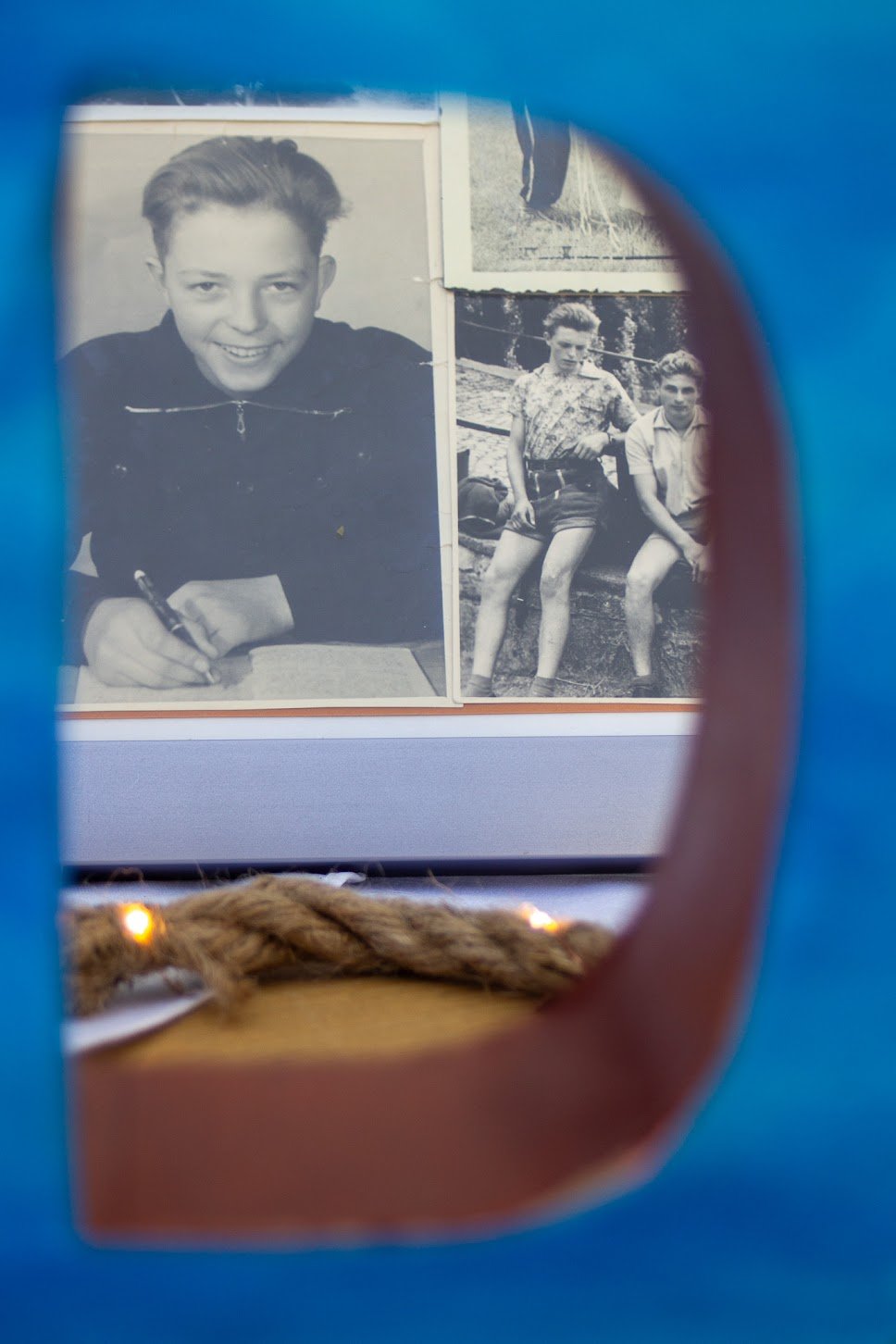 Schwarz-Weiß-Foto von einem Jungen, der schreibt, eingefasst in eine blaue und braune Rahmenöffnung.
