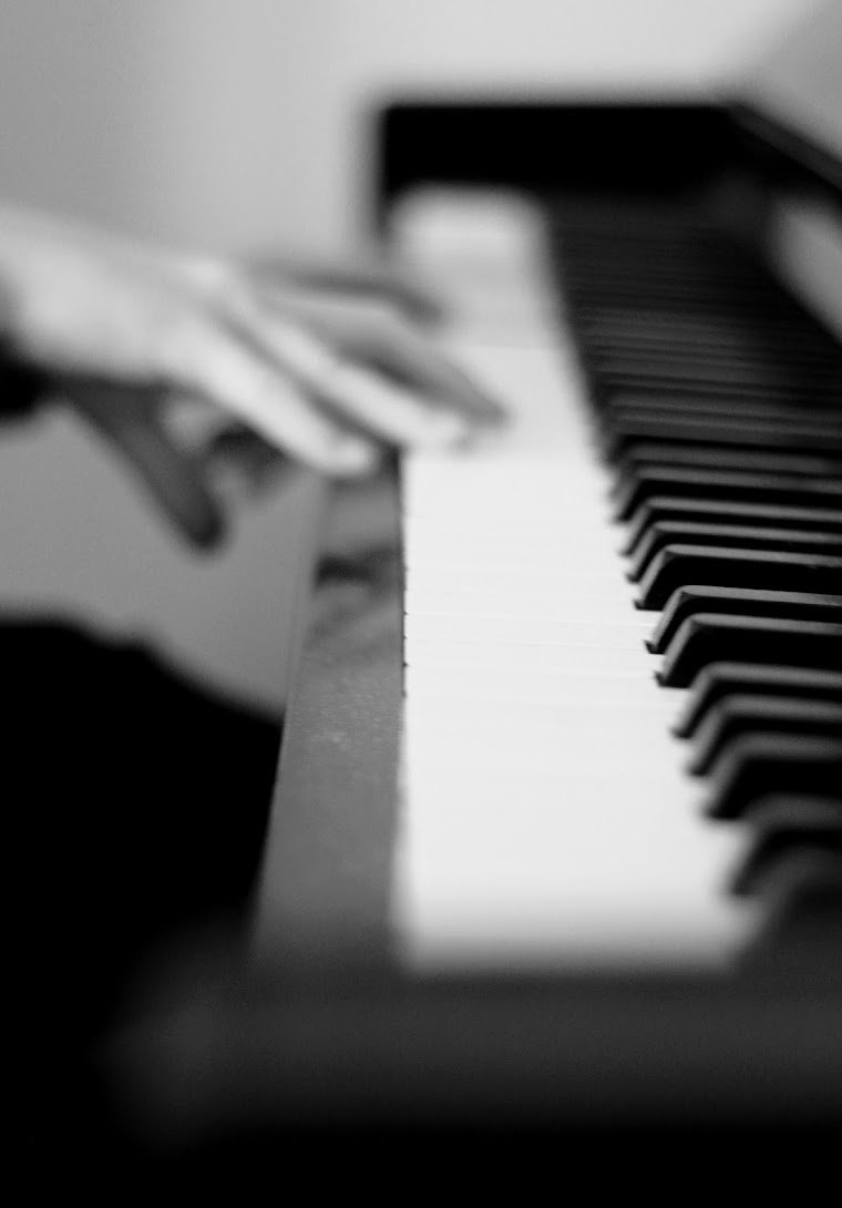 Schwarz-weiße Aufnahme eines Klaviers mit Händen die auf den Tasten spielen.