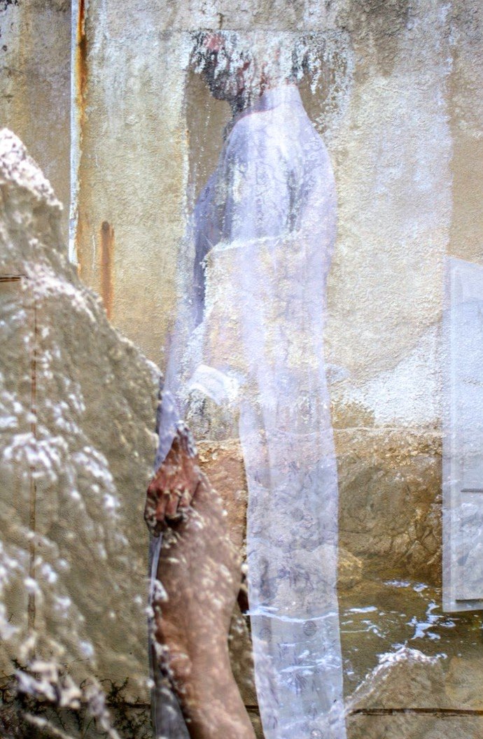 Street Kunst, das eine Figur mit weißen Gewand zeichnet, durch eine Scheibe fotografiert, die den Blick auf die Figur leicht verwischt.