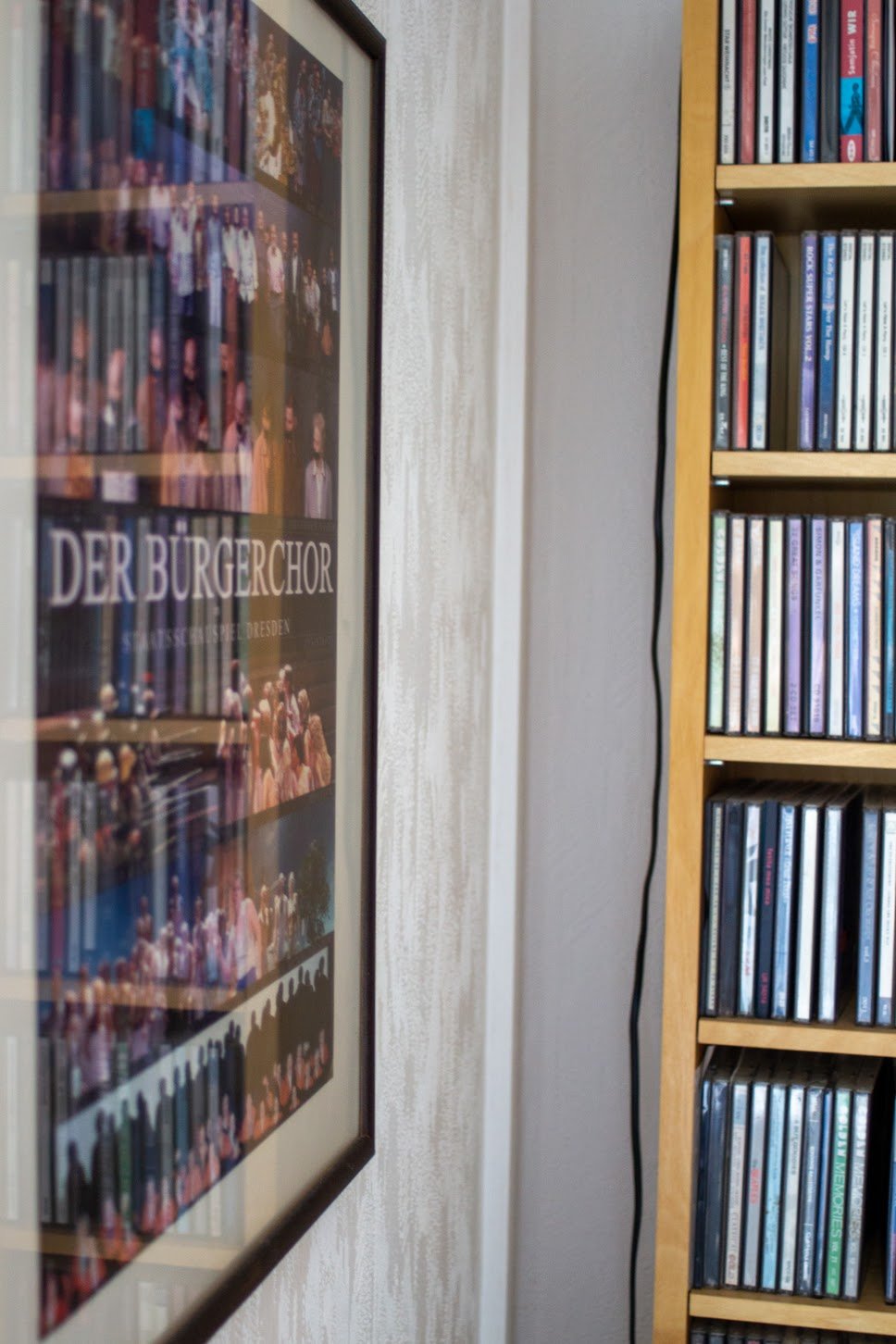 Ein Poster für den Bürgerchor Dresden neben einem Bücherregal mit CDs