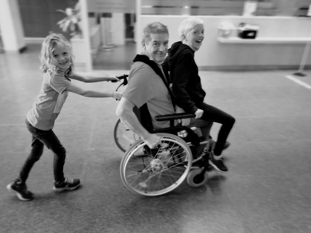 Ein Mädchen schiebt den Rollstuhl durch ein Krankenhaus.