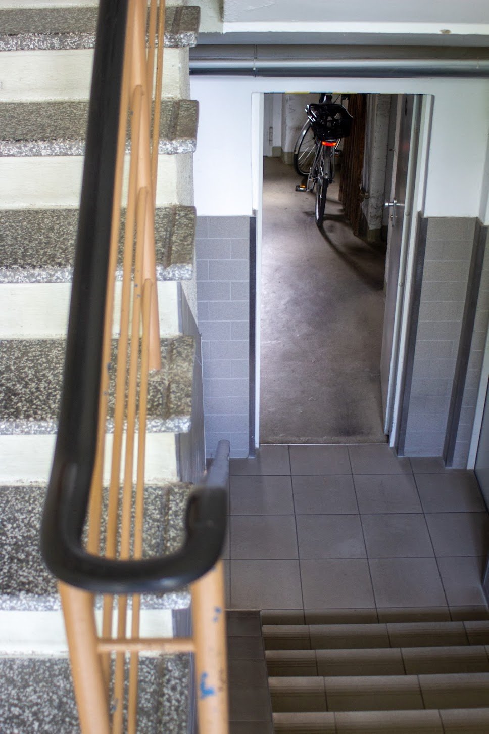 Blick von einer Treppe nach unten in einen Flur mit Fahrrad in einer Garage.