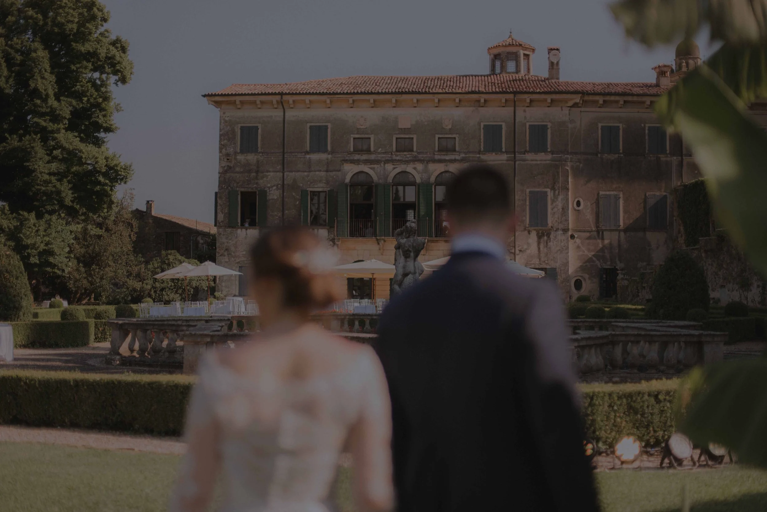 Braut und Bräutigam gehen während einer Sommerhochzeit durch den Garten der Villa Verità Fraccaroli in Verona, Italien. Bride and groom walking through the garden of Villa Verità Fraccaroli in Verona, Italy, during a summer wedding.