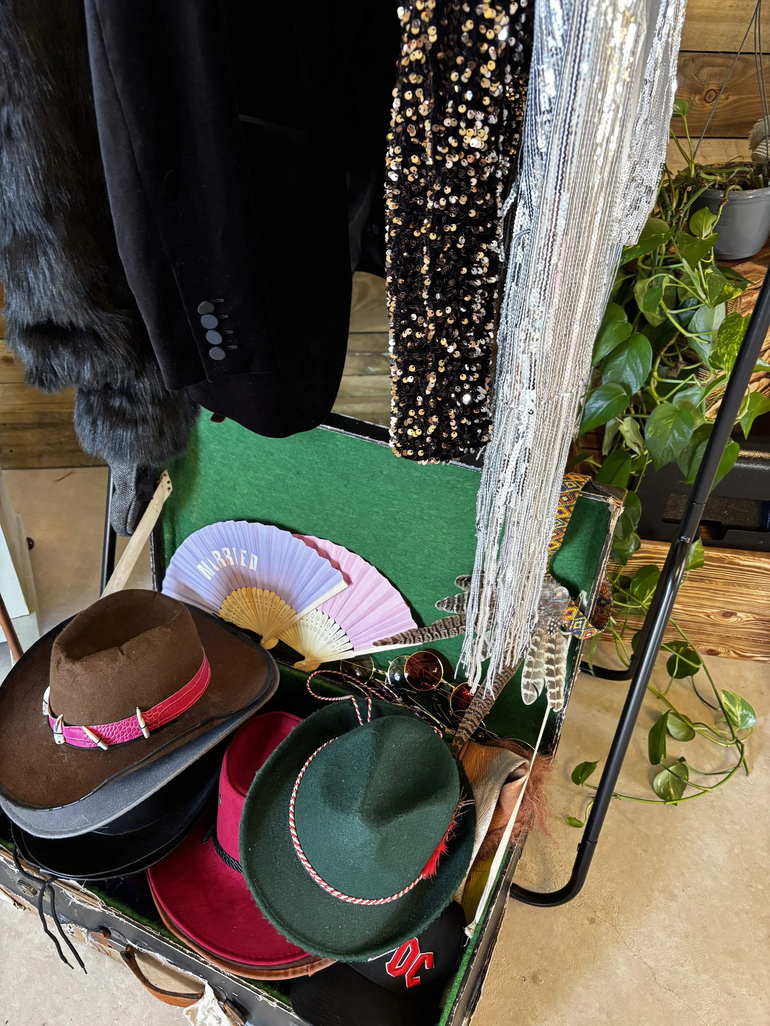 Display of various photo booth props including hats, sunglasses, fans, scarves, feathers, and clothing items, all in a vintage style.