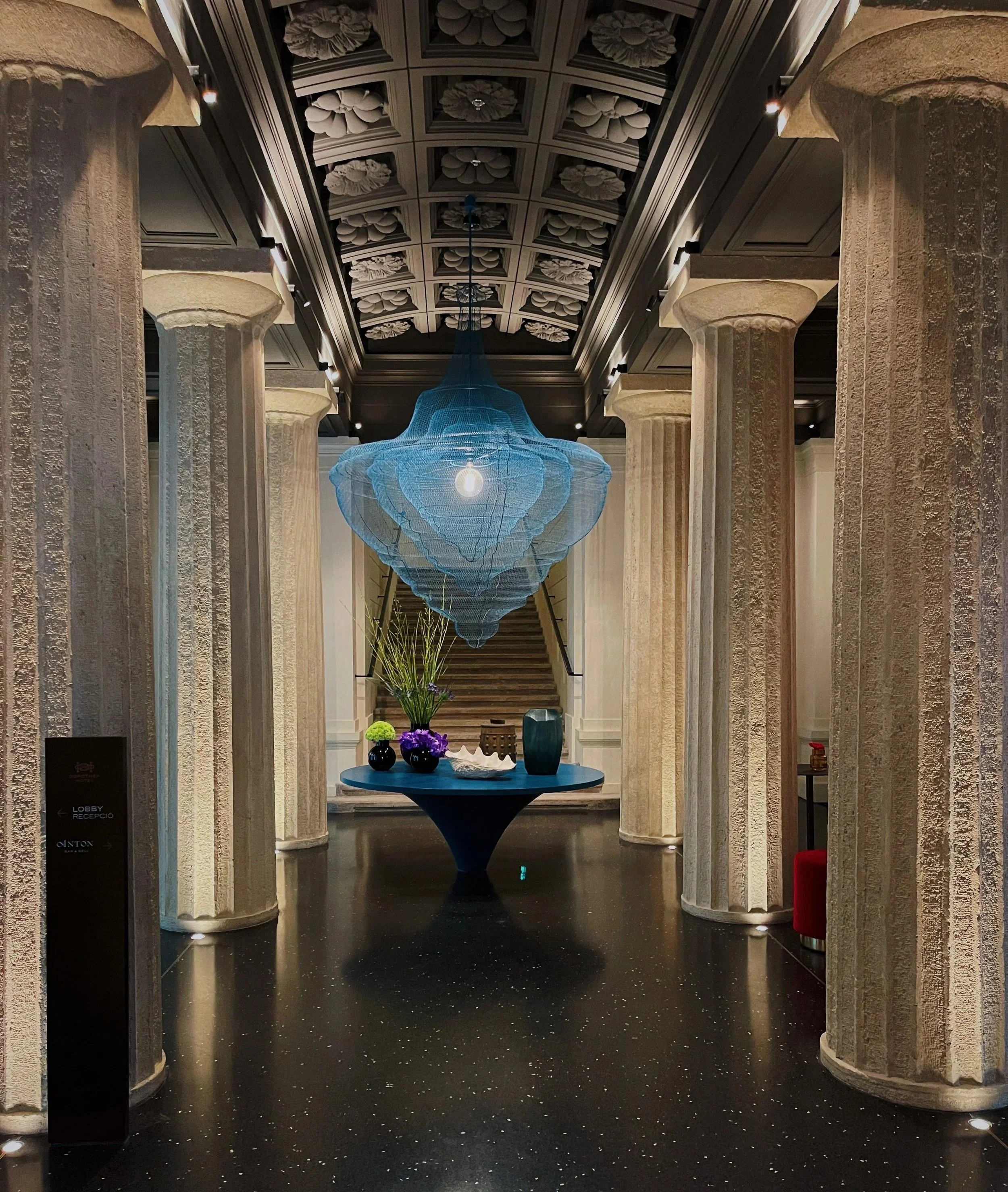 Grand entrance hall of Dorothea Hotel in Budapest with sculptural chandelier and ornate architectural detailing photographed by hospitality photographer Natalia Moreno.