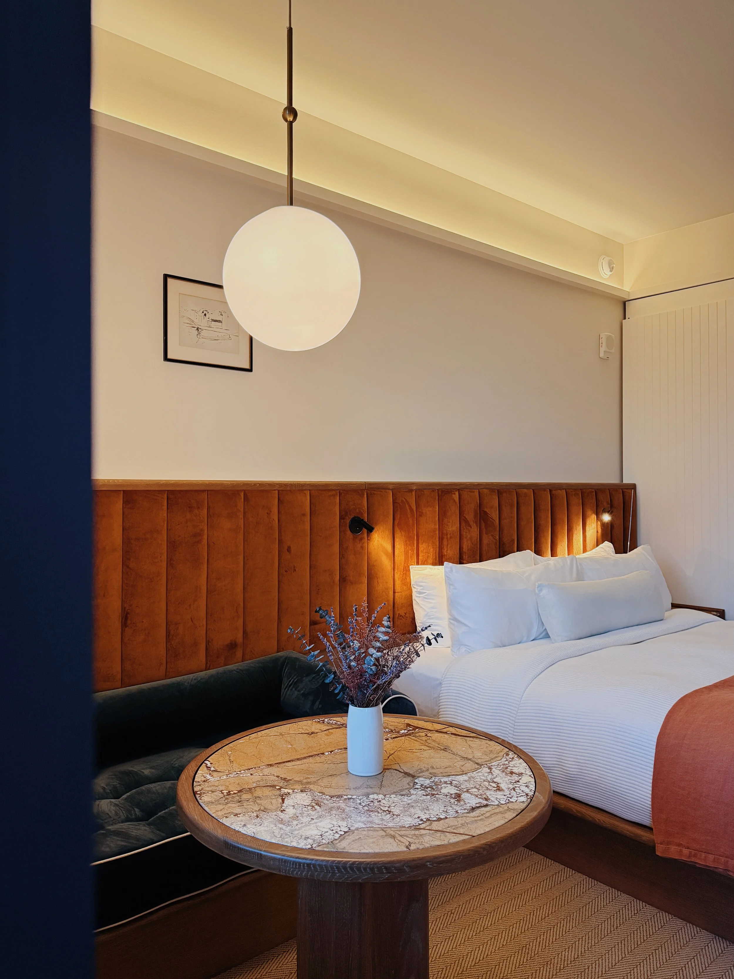 Boutique hotel bedroom at Hotel Henrietta New Orleans with warm lighting and mid-century furnishings photographed by Natalia Moreno.