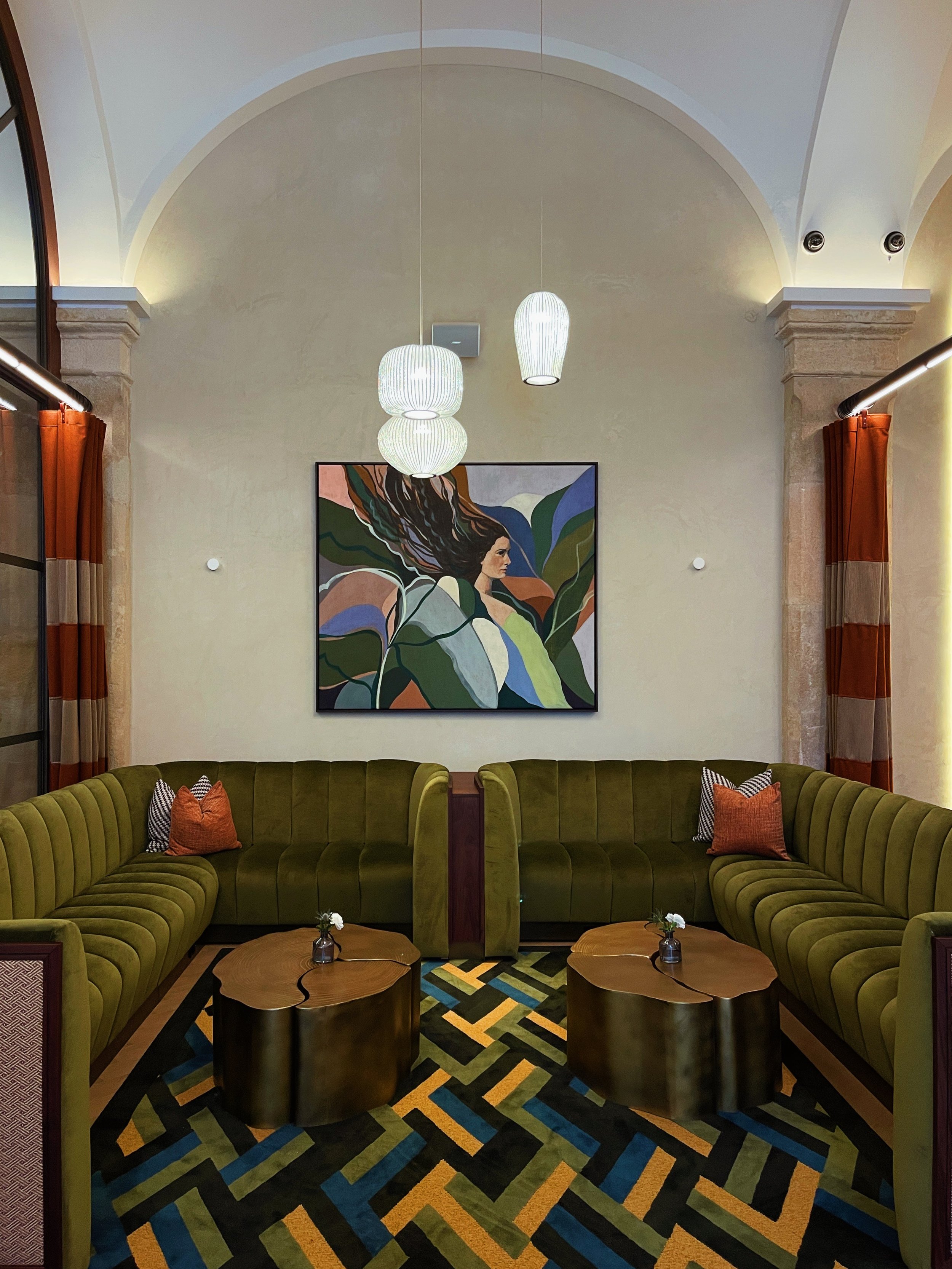 Double-height lounge at Riding School Vienna hotel showcasing vaulted ceilings, contemporary artwork, and refined architectural hospitality design
