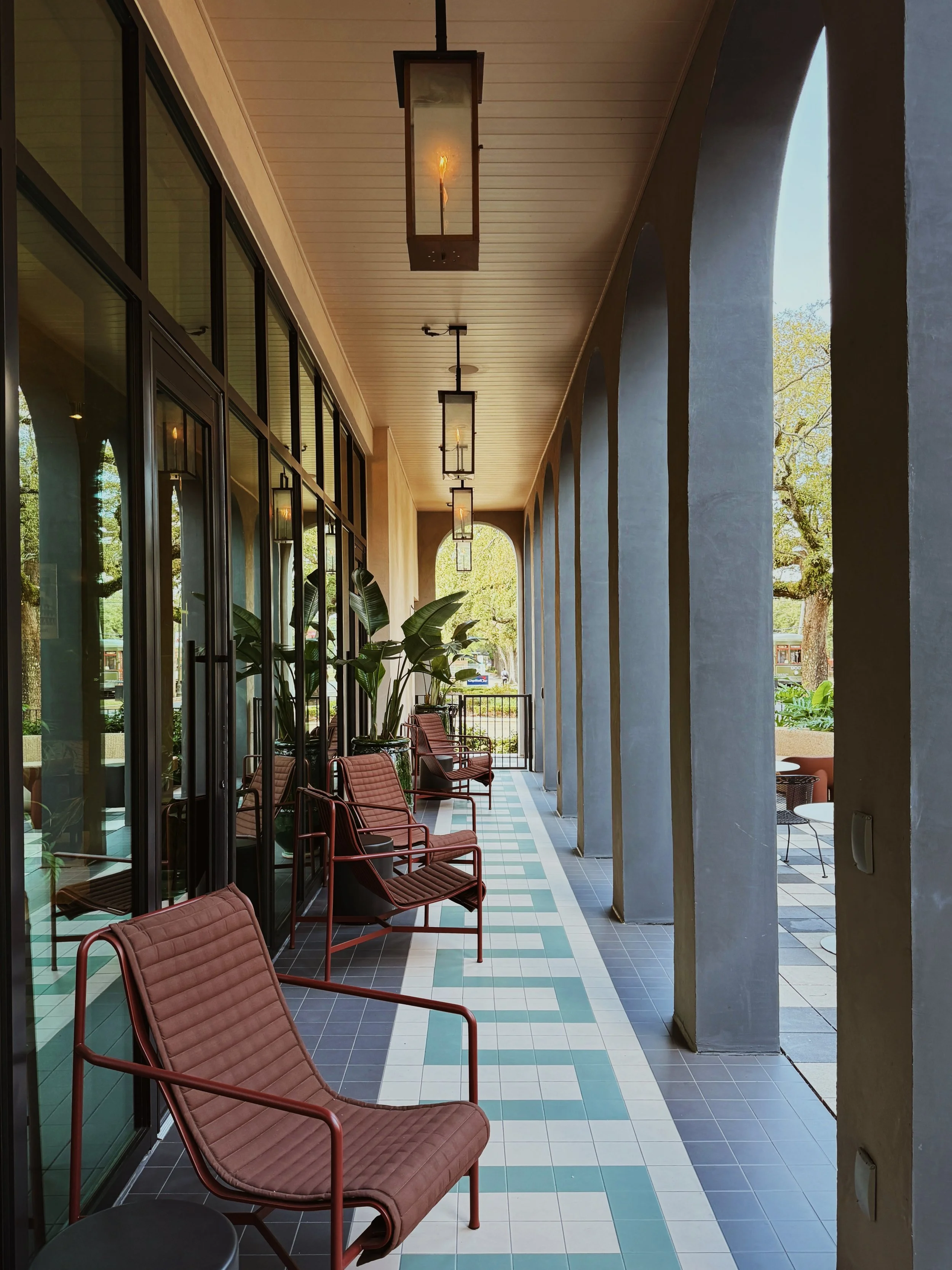 Exterior corridor at Hotel Henrietta in New Orleans featuring tiled flooring and shaded seating photographed by hospitality photographer Natalia Moreno.