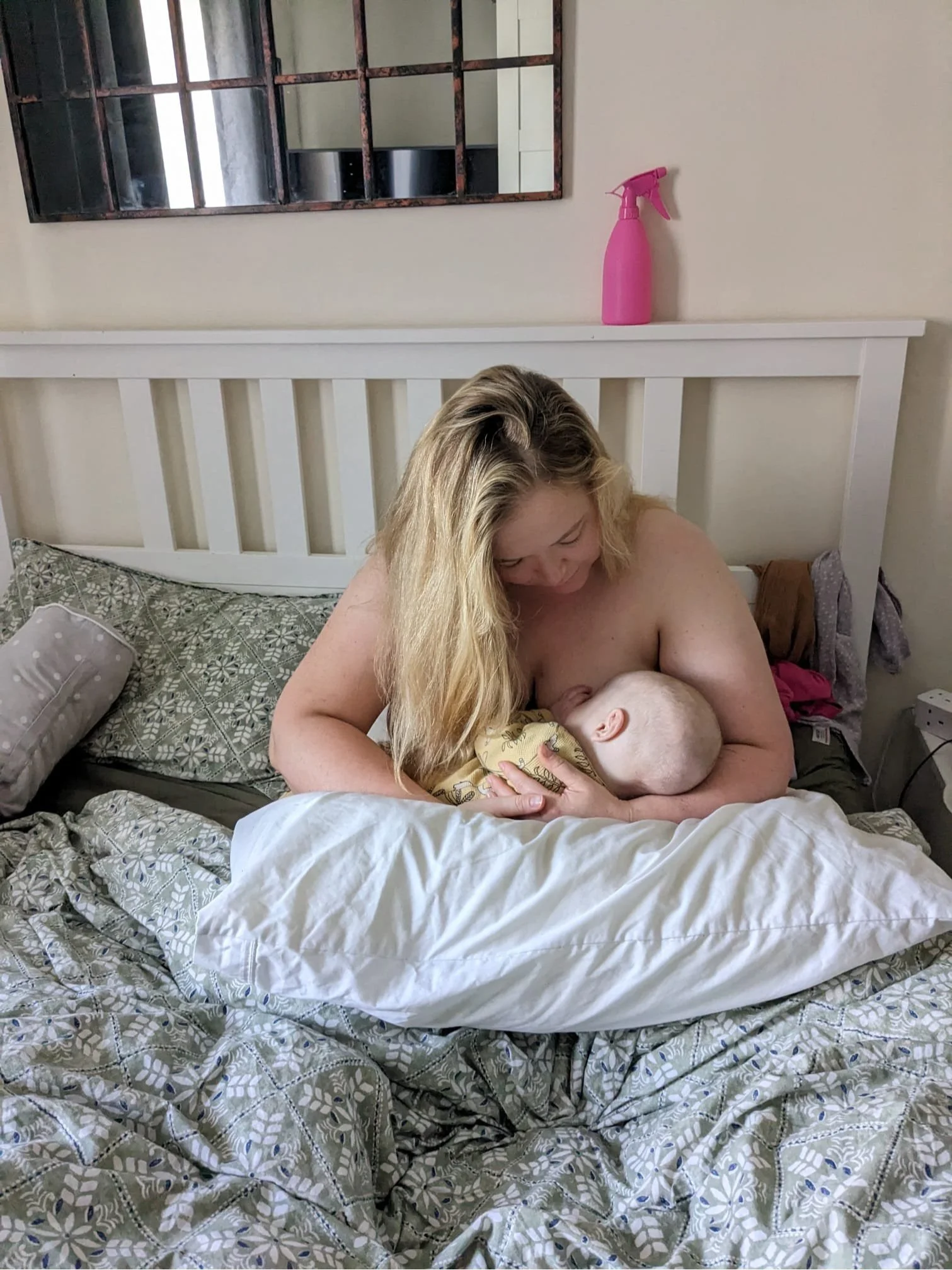 A blonde mother breastfeeding a baby in bed
