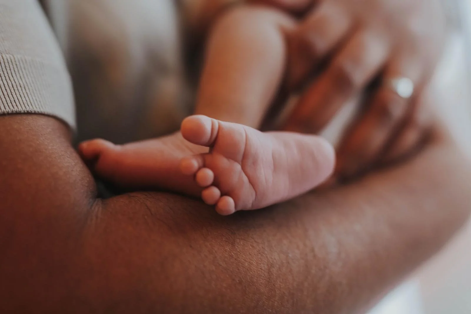 Close-up of a baby's tiny hand grasping an adult's finger.