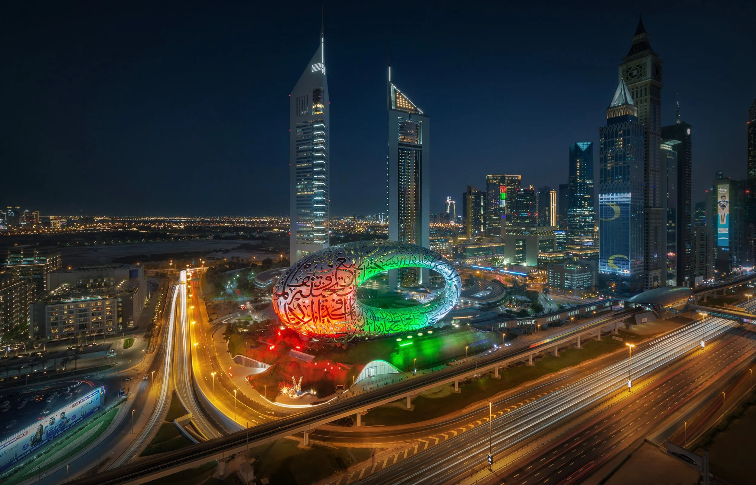 Nighttime panoramic view of Dubai city skyline featuring the Museum of the future with UAE colors - fine art architectural photograph by Ahmad Alnaji, SARAB Art Production