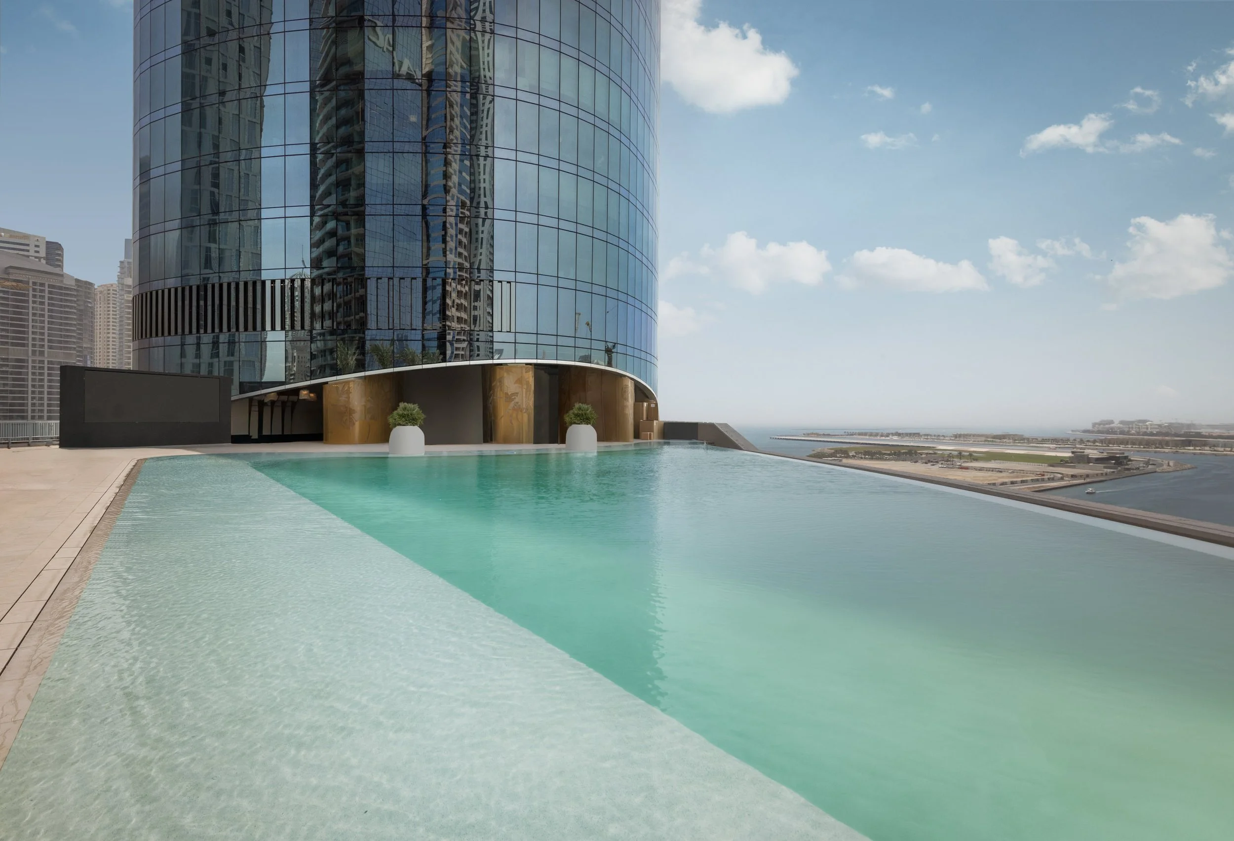 The infinity pool on the podium deck of Ciel Dubai Marina, the tower rising directly behind it.