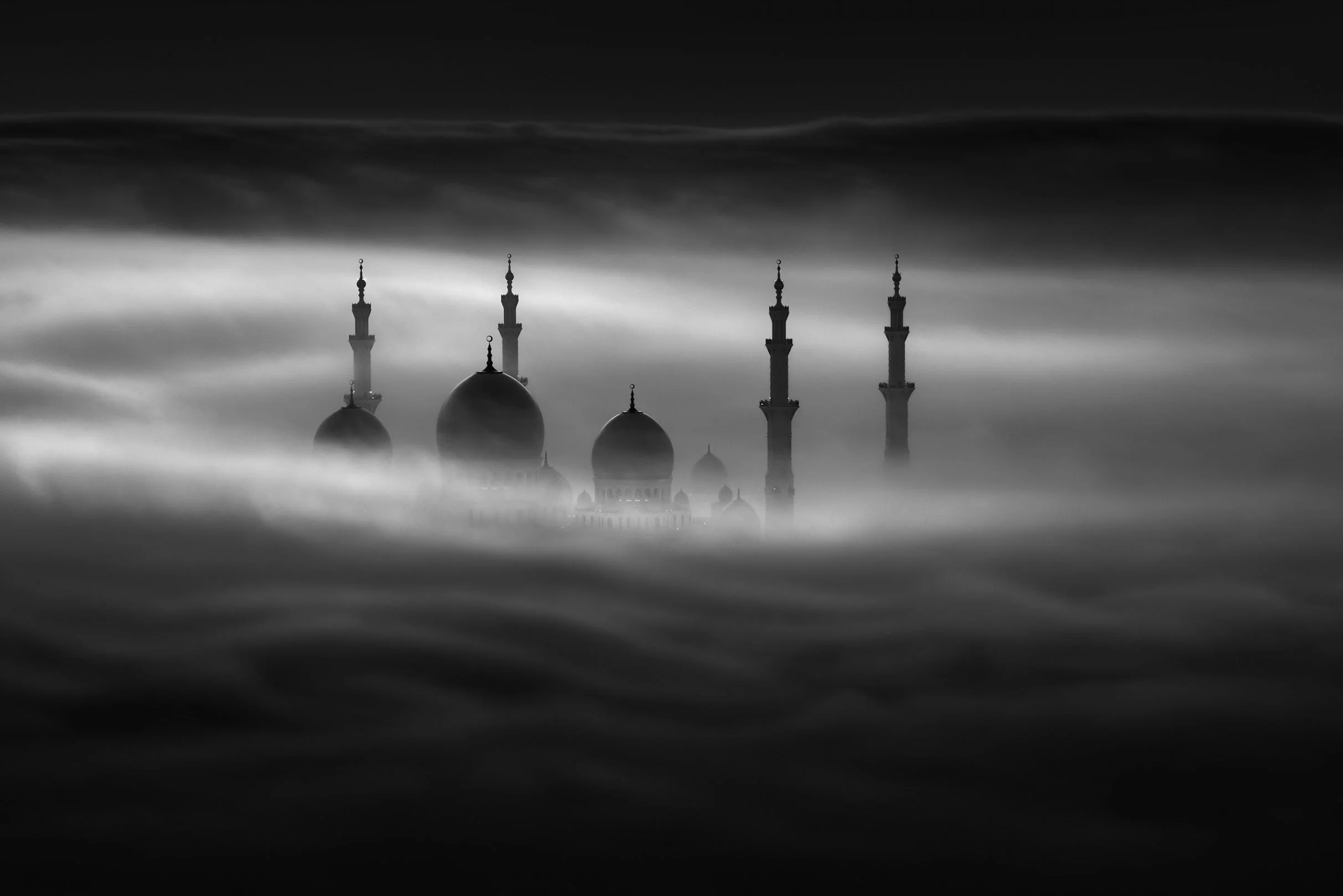 Black and white photo of Sheikh Zayed grand mosque in Abu Dhabi with domes and minarets surrounded by fog -  photograph by Khalid Alhammadi, SARAB Art Production