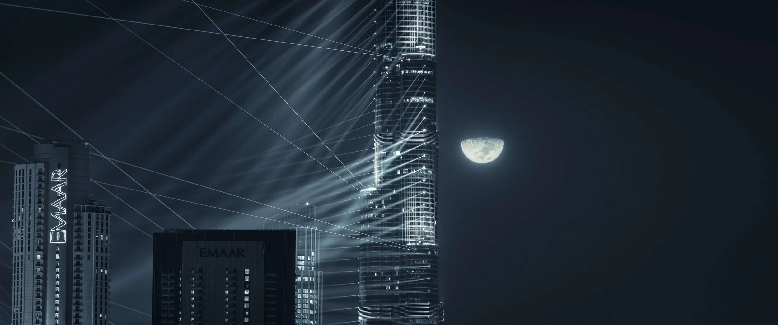 Nighttime Dubai cityscape with Burj Khalifa light show and the moon and Emaar logo - fine art photograph by Ahmad Alnaji, SARAB Art Production