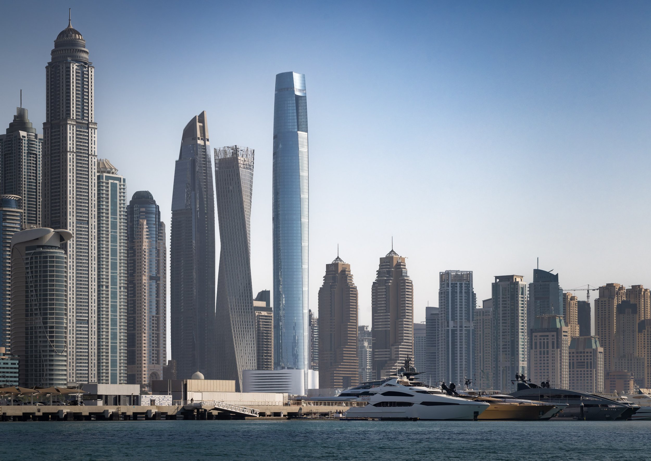 Ciel Dubai Marina by NORR seen across open water on a clear day, a yacht berthed at the quay below.