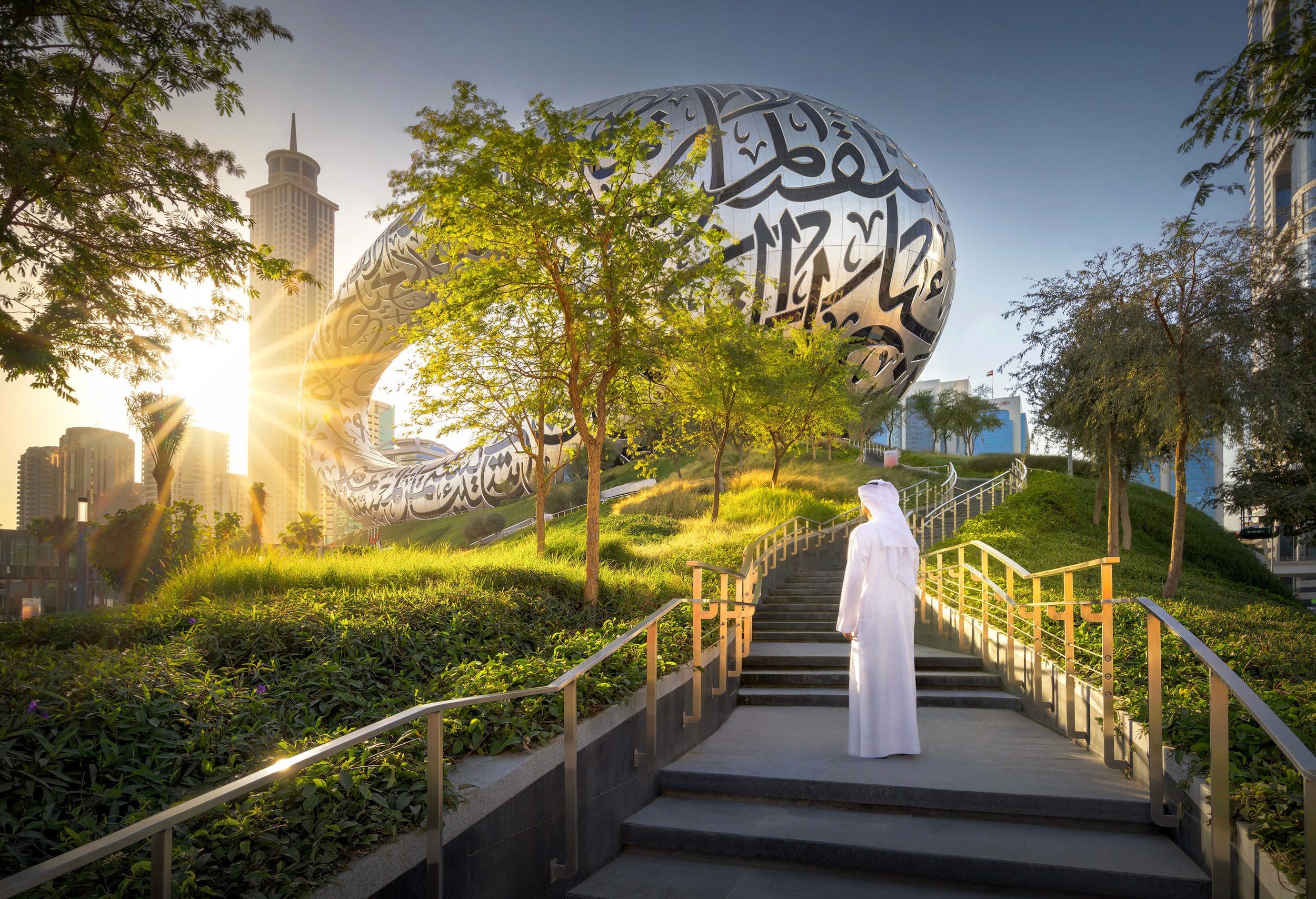 Museum of the Future exterior at sunset with Emirati man walking toward the building, Dubai — fine art architectural photograph by Ahmad Alnaji, SARAB Art Production