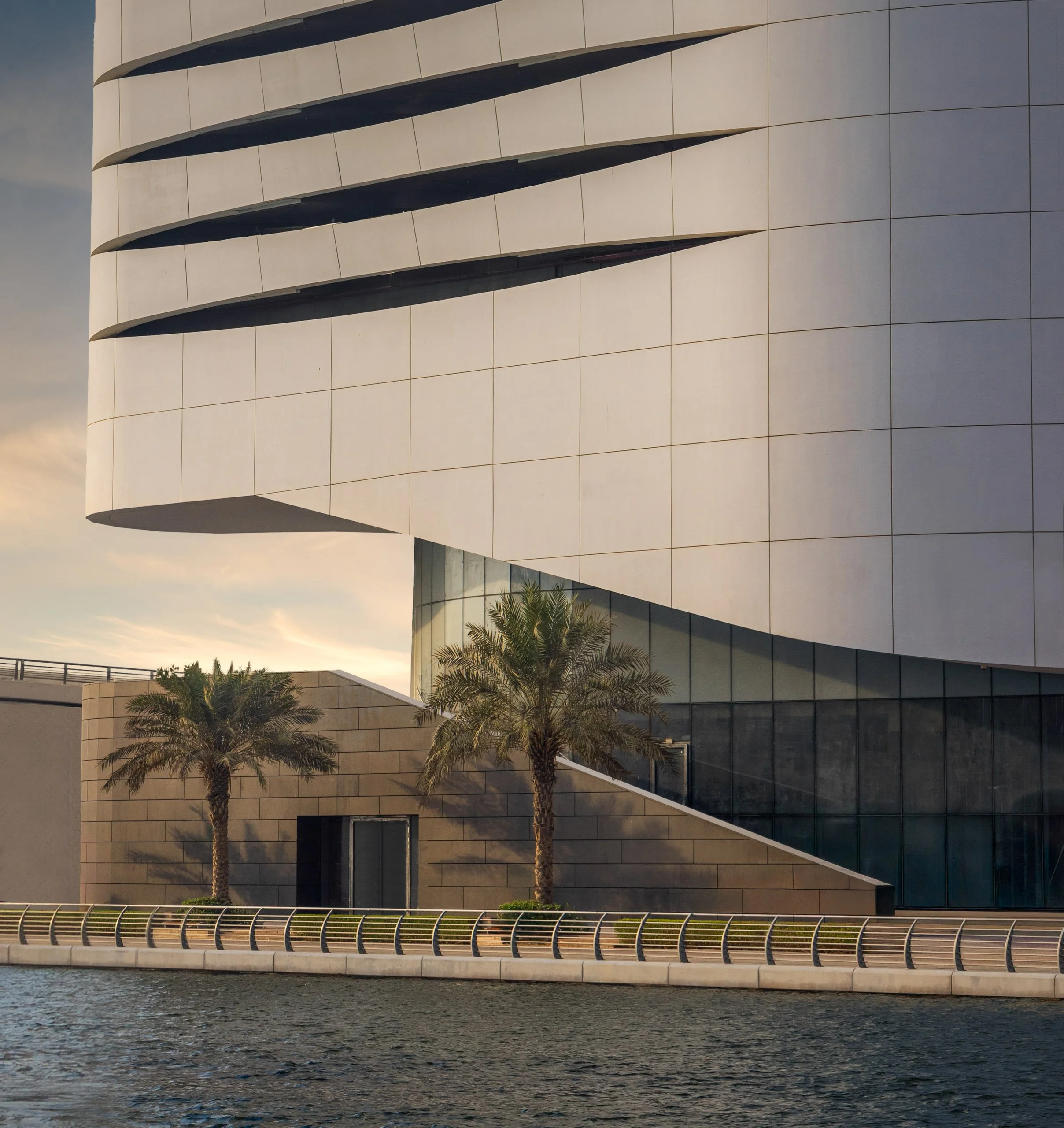 The underside of the Ciel Dubai Marina podium at dusk, angled columns carrying the deck above the entrance.
