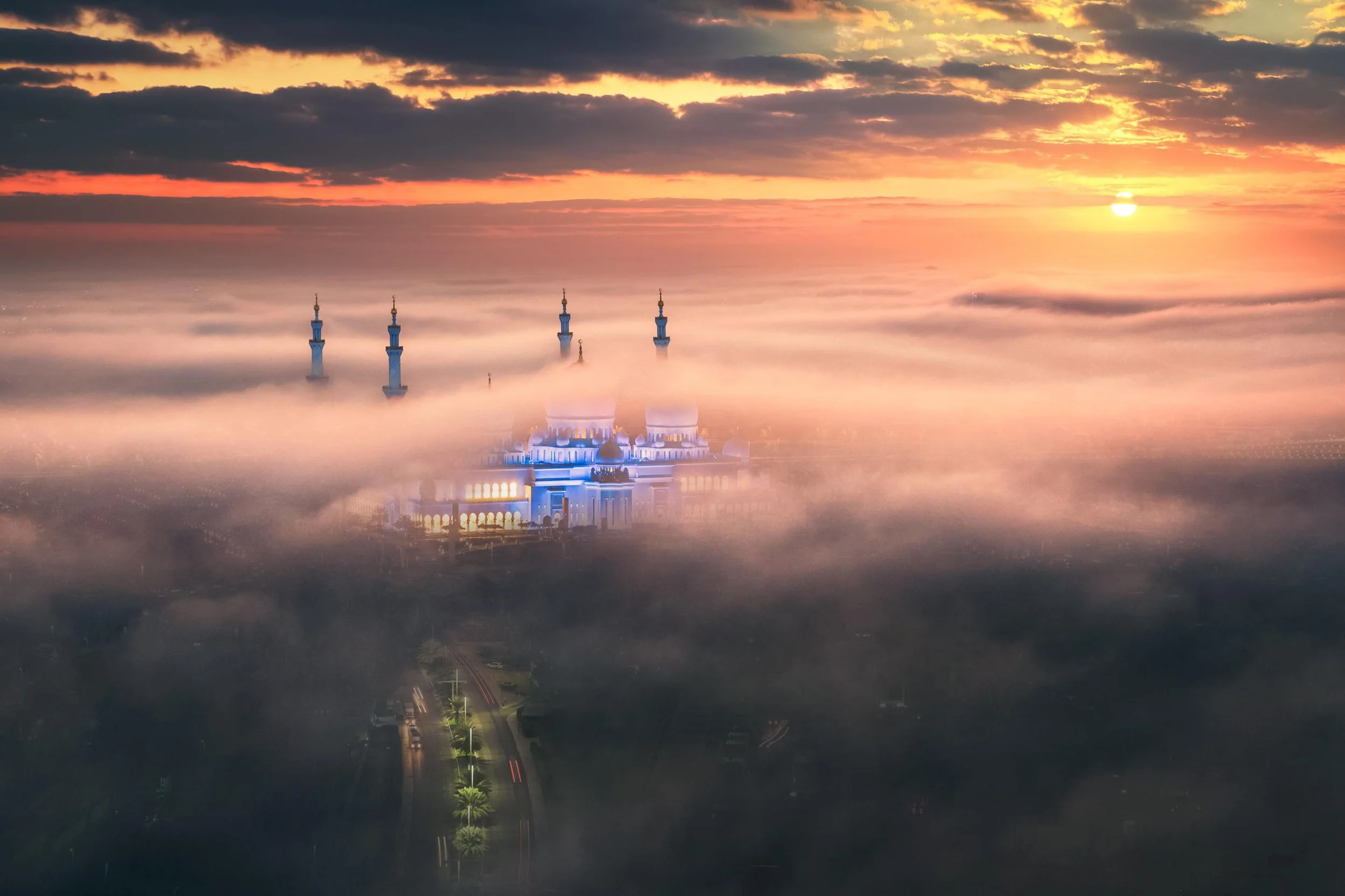 Sheikh Zayed grand mosque in Abu Dhabi at sunrise, emerging from a sea of clouds - photograph by Khalid Alhammadi, SARAB Art Production