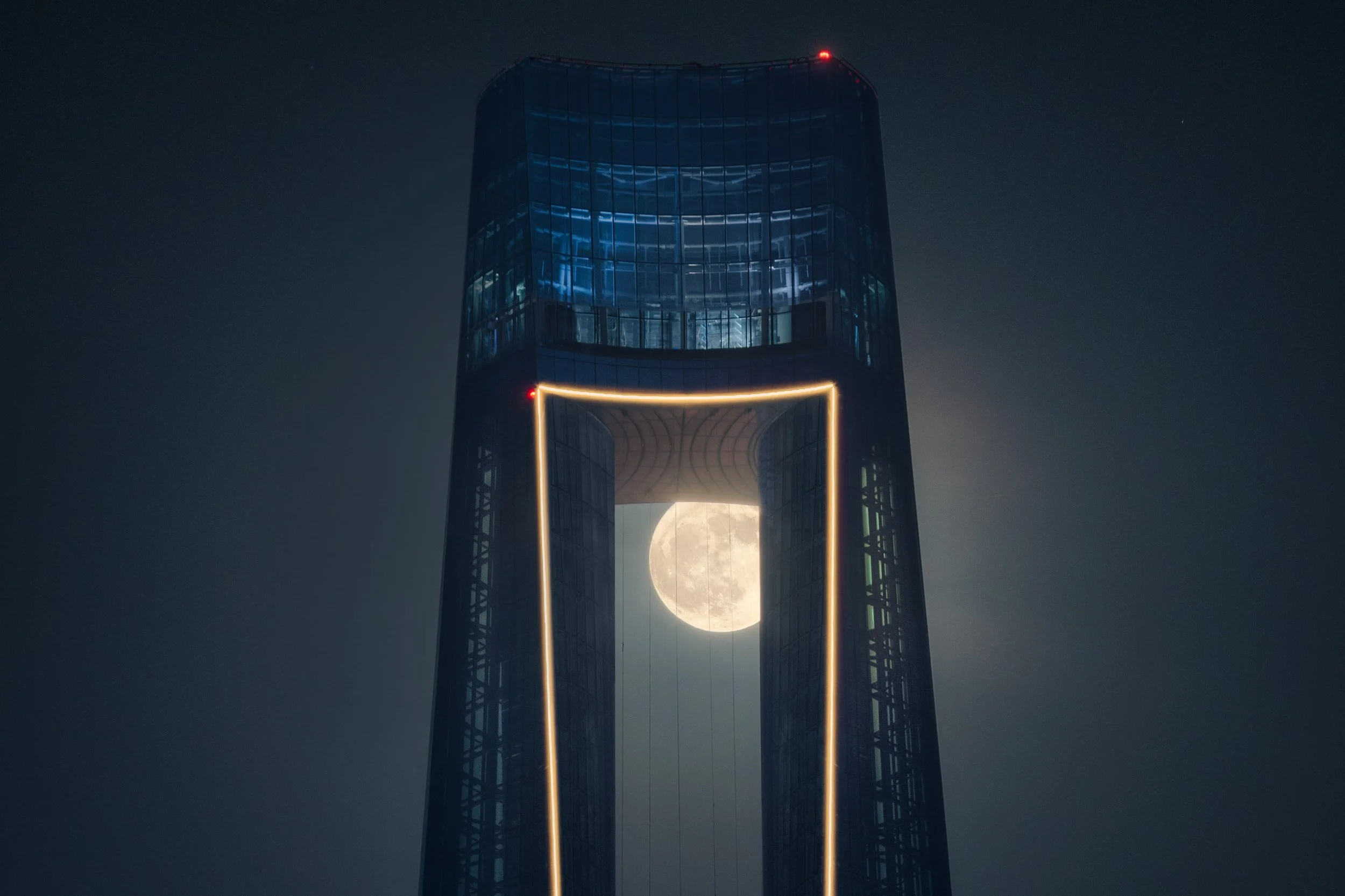 Close view of the crown of Ciel Dubai Marina with the moon held inside the lit aperture.