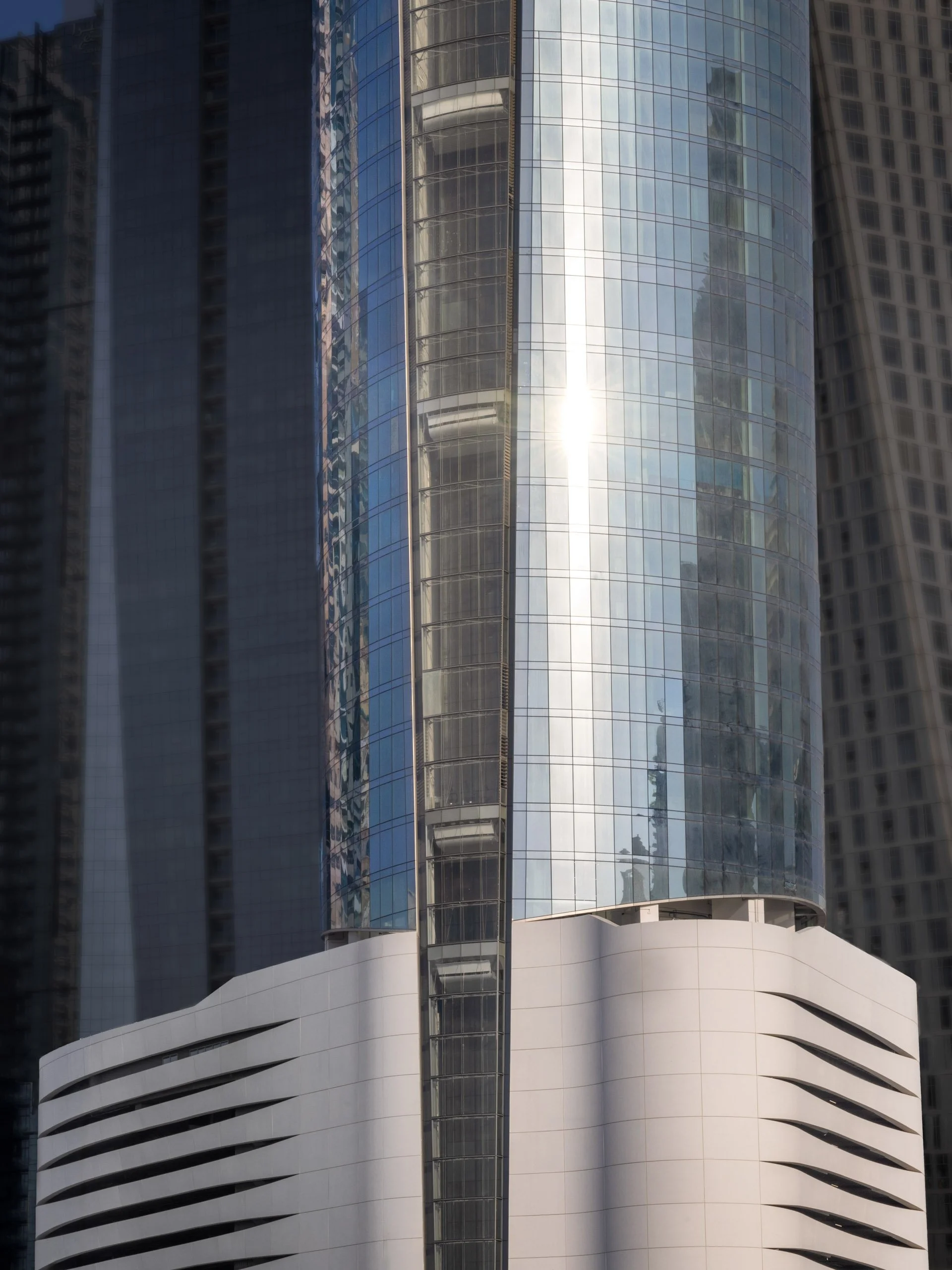 Sunlight moving across the curved glass of Ciel Dubai Marina above the white podium.