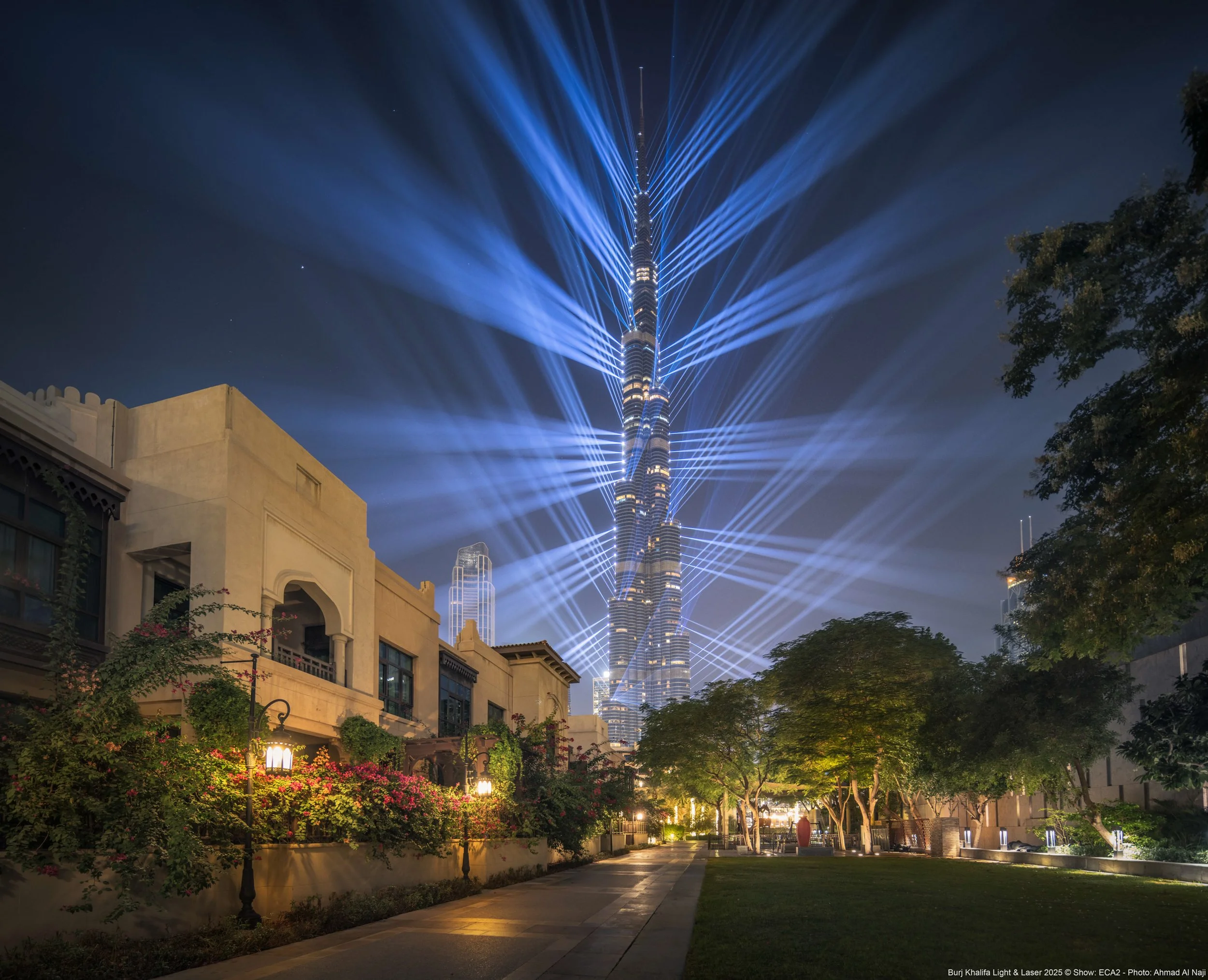 Night view of the Burj Khalifa in Dubai illuminated with laser light beams radiating outward - fine art drone photograph by Ahmad Alnaji, SARAB Art Production