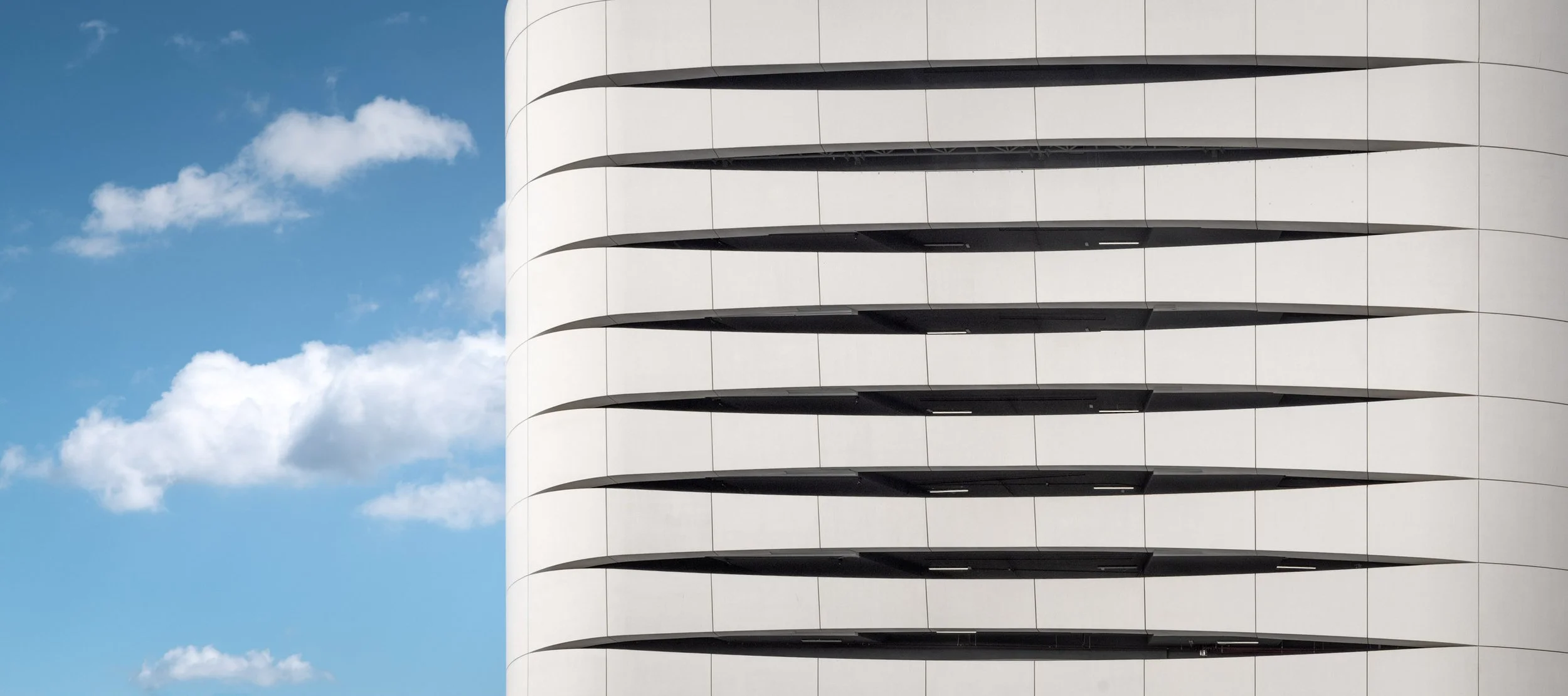 The podium louvres of Ciel Dubai Marina by NORR set against a blue sky with cloud.
