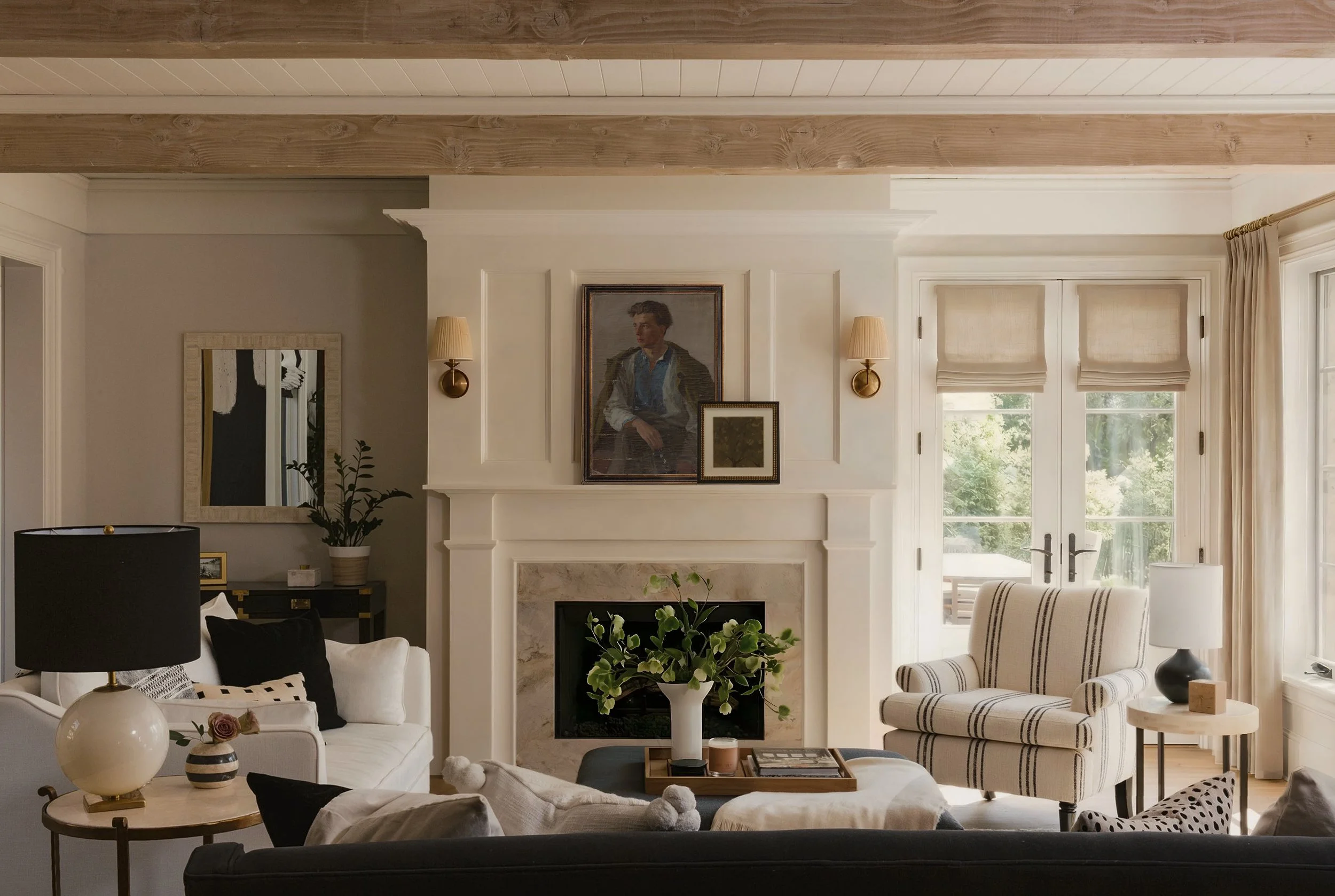 Living room with white sofa, striped armchair, fireplace, and large windows letting in natural light. Designer servicing Westchester County, NY, and Fairfield County, CT. 
