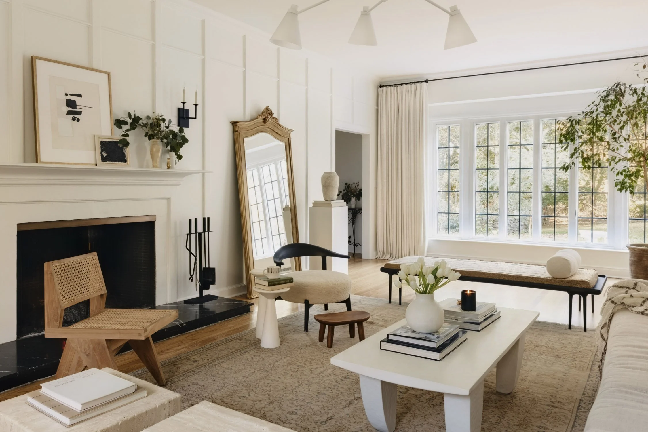 Living room with a large window, white walls, modern furniture, a fireplace, and various decorative items. Designer servicing Westchester County, NY, and Fairfield County, CT. 