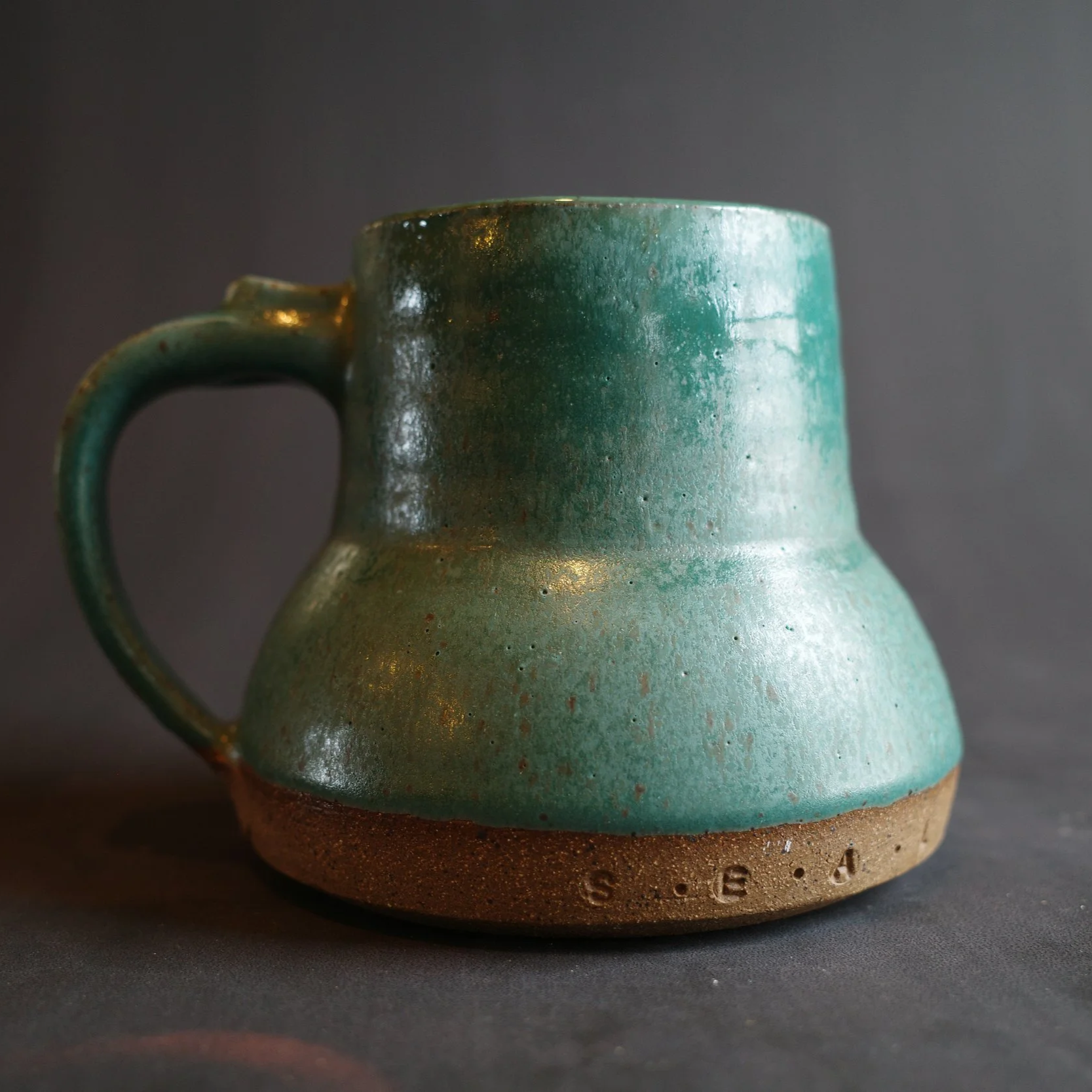 Green ceramic mug with a handle and a wider bottom
