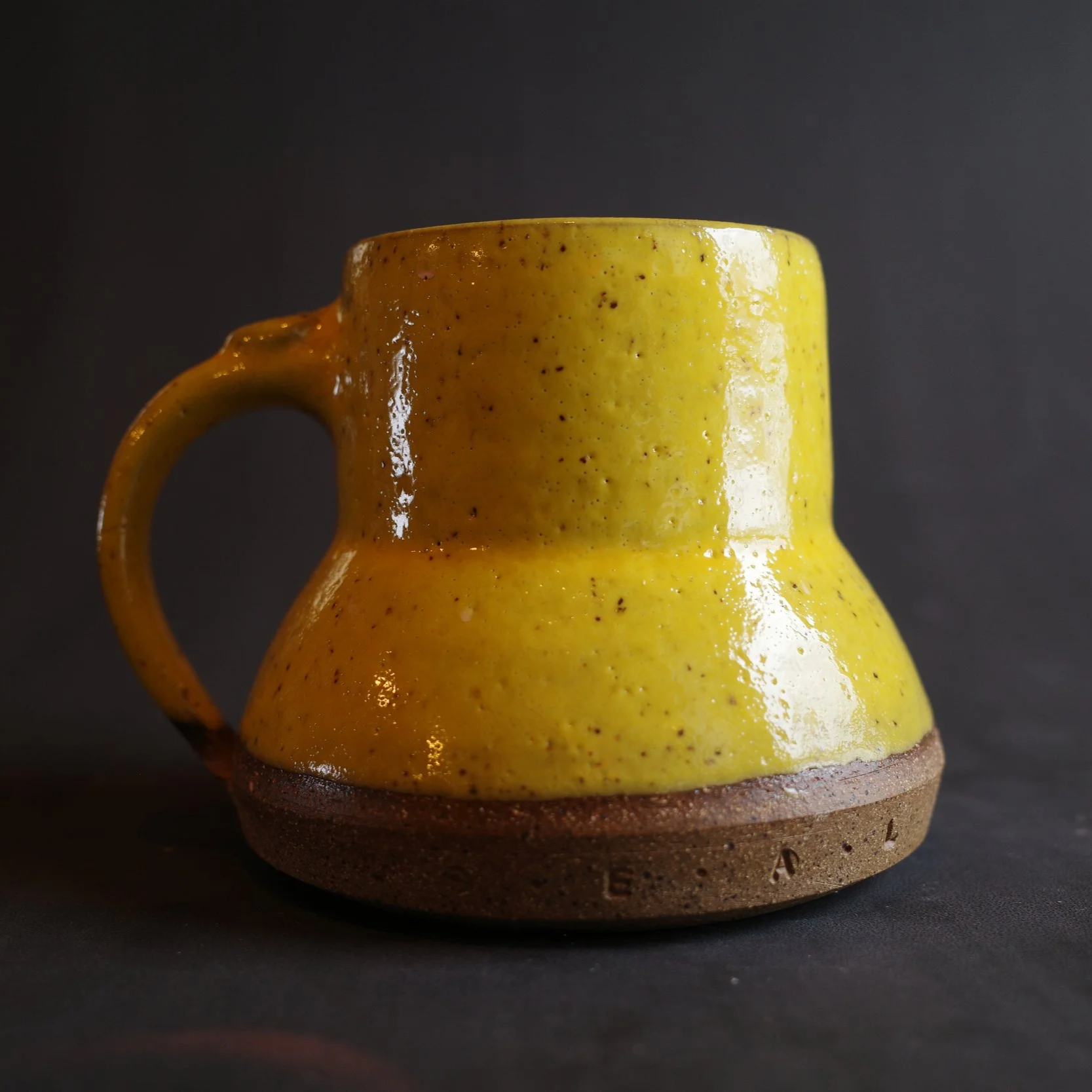 Yellow ceramic mug with a handle and a wider bottom
