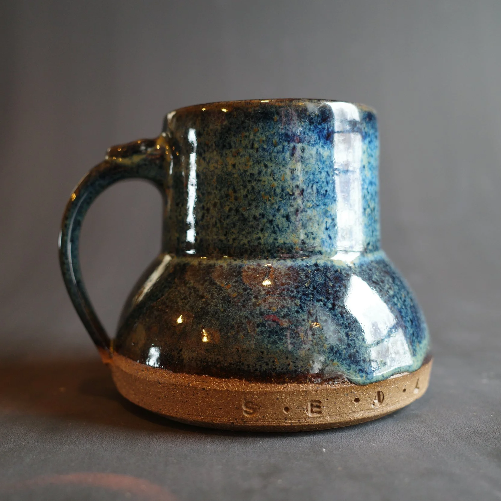 Blue ceramic mug with a handle and a wider bottom