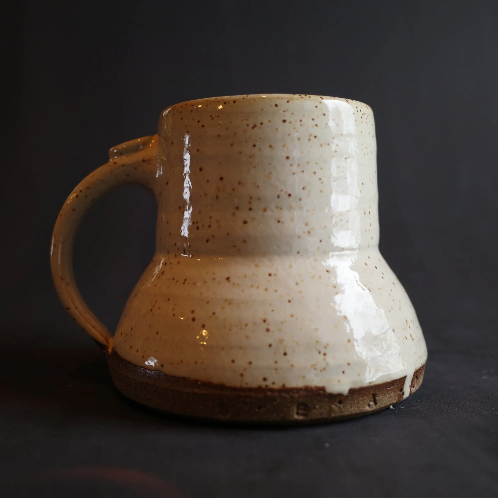 Cream ceramic mug with a handle and a wider bottom