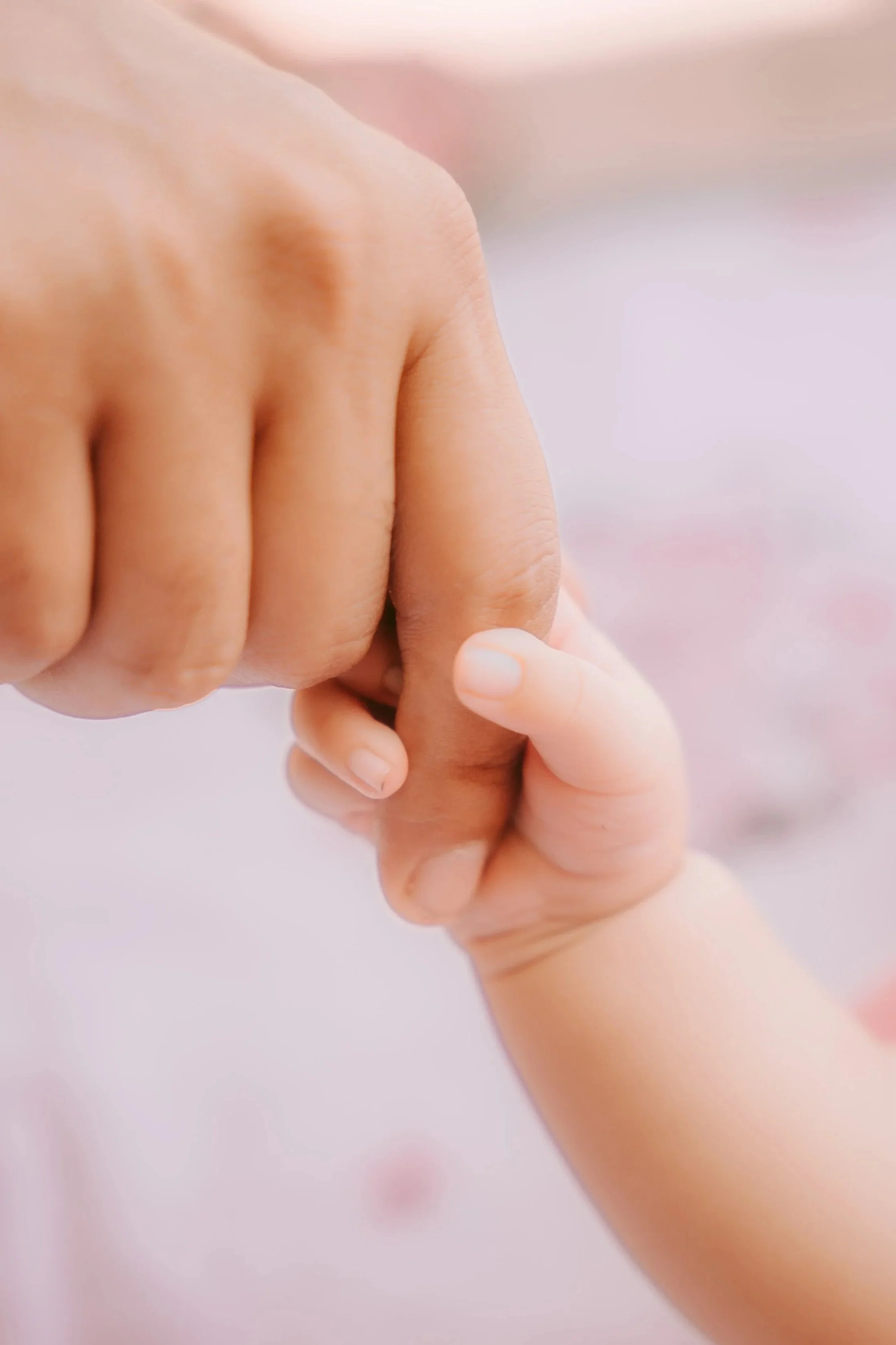 A postpartum doula holding a newborn baby's hand.