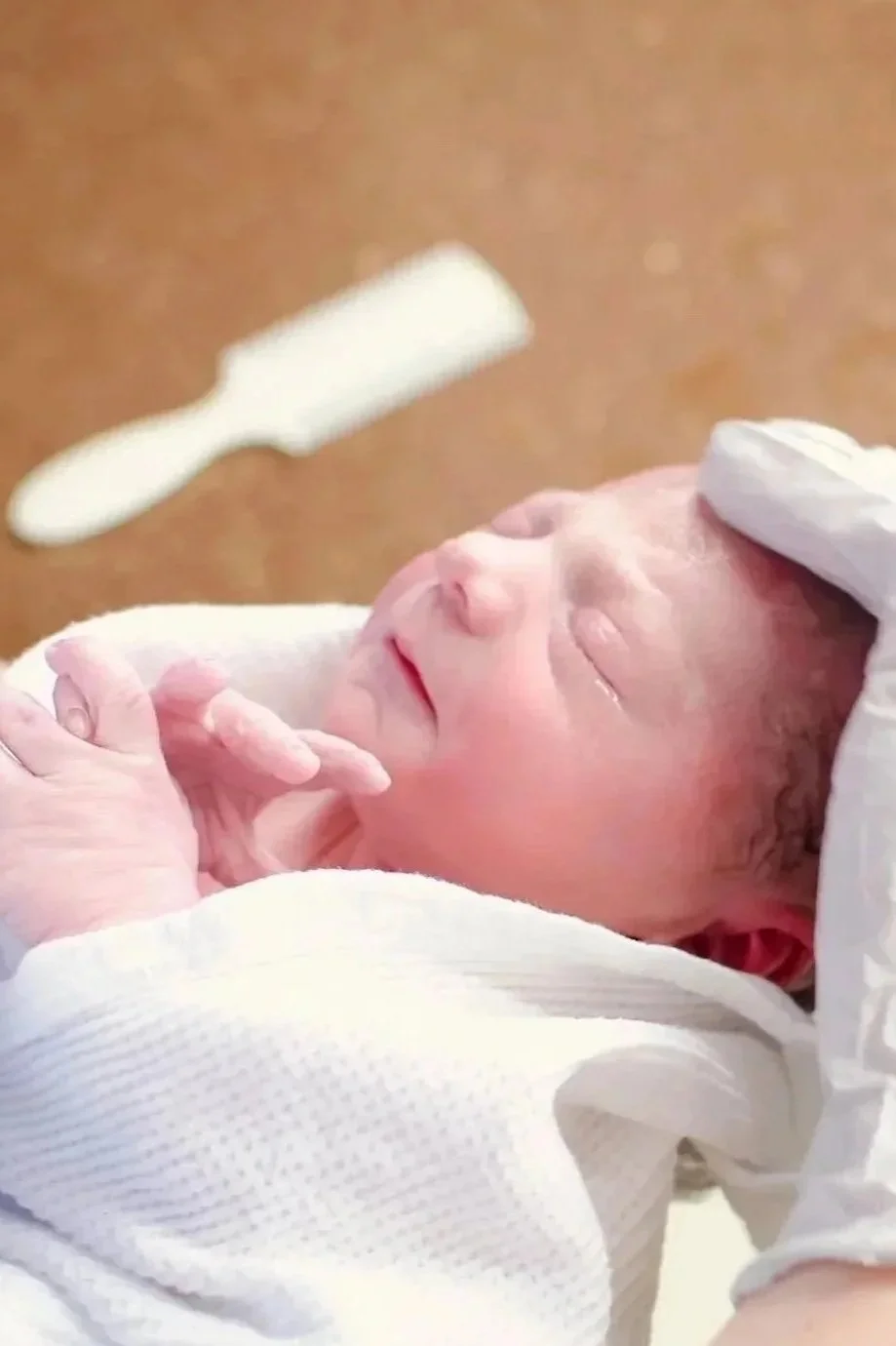 A postpartum doula gently gives a newborn baby their first bath. Parents watch nearby for education.
