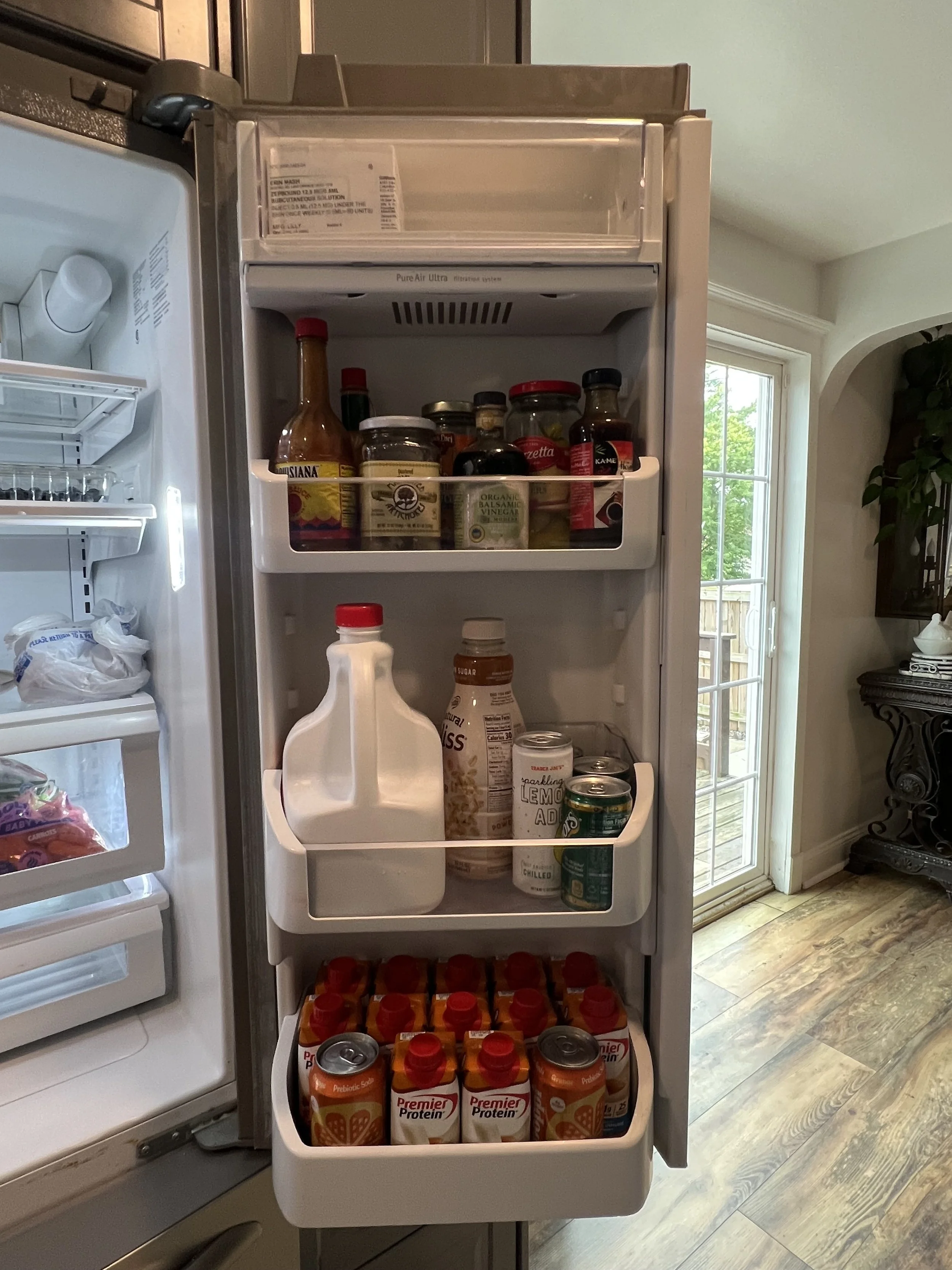 Open refrigerator door showing shelves with sauces, drinks, and food items.