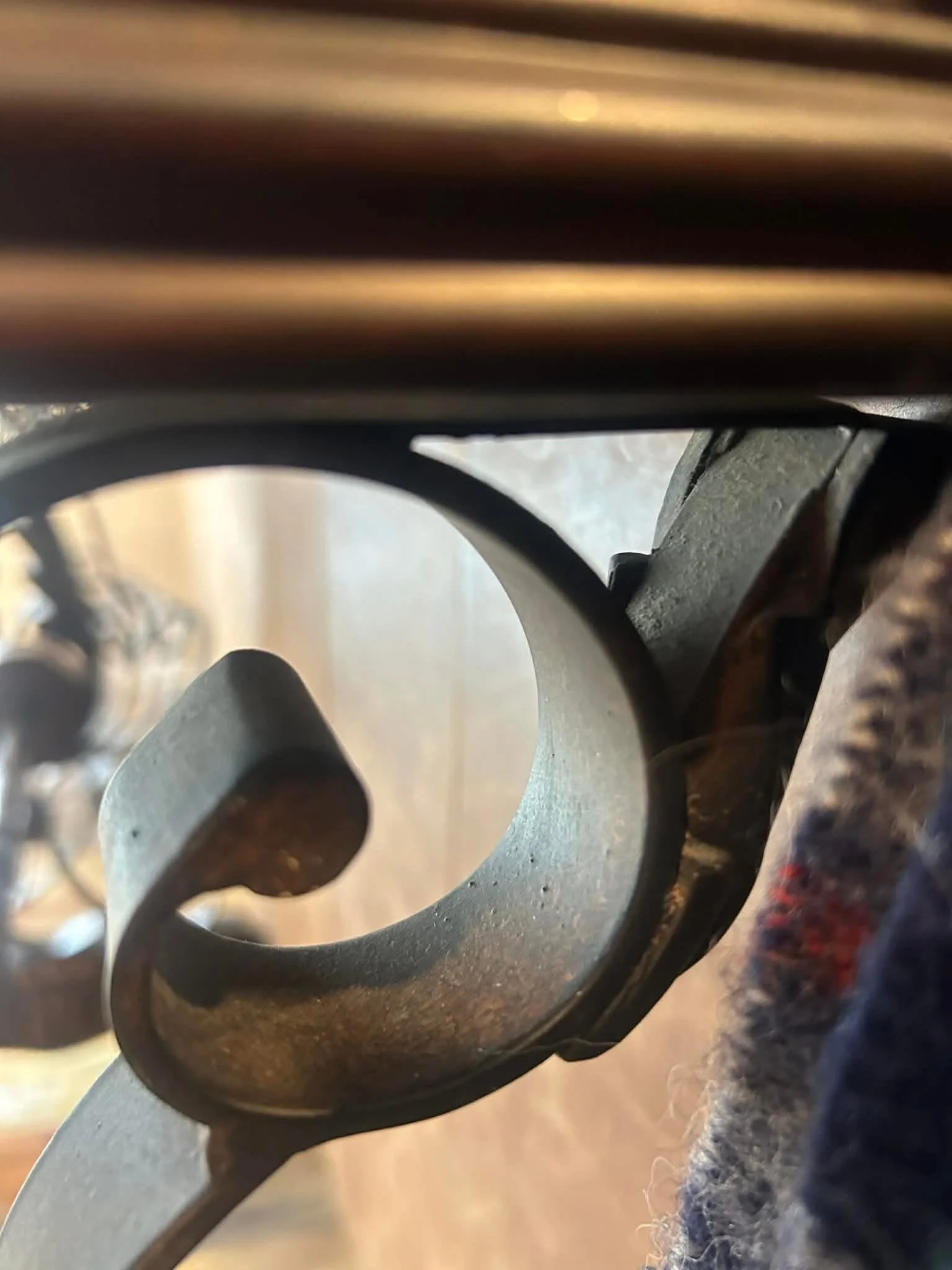 Close-up photo of a rusty, metal spiral staircase or railing, viewed from underneath, with blurred background.