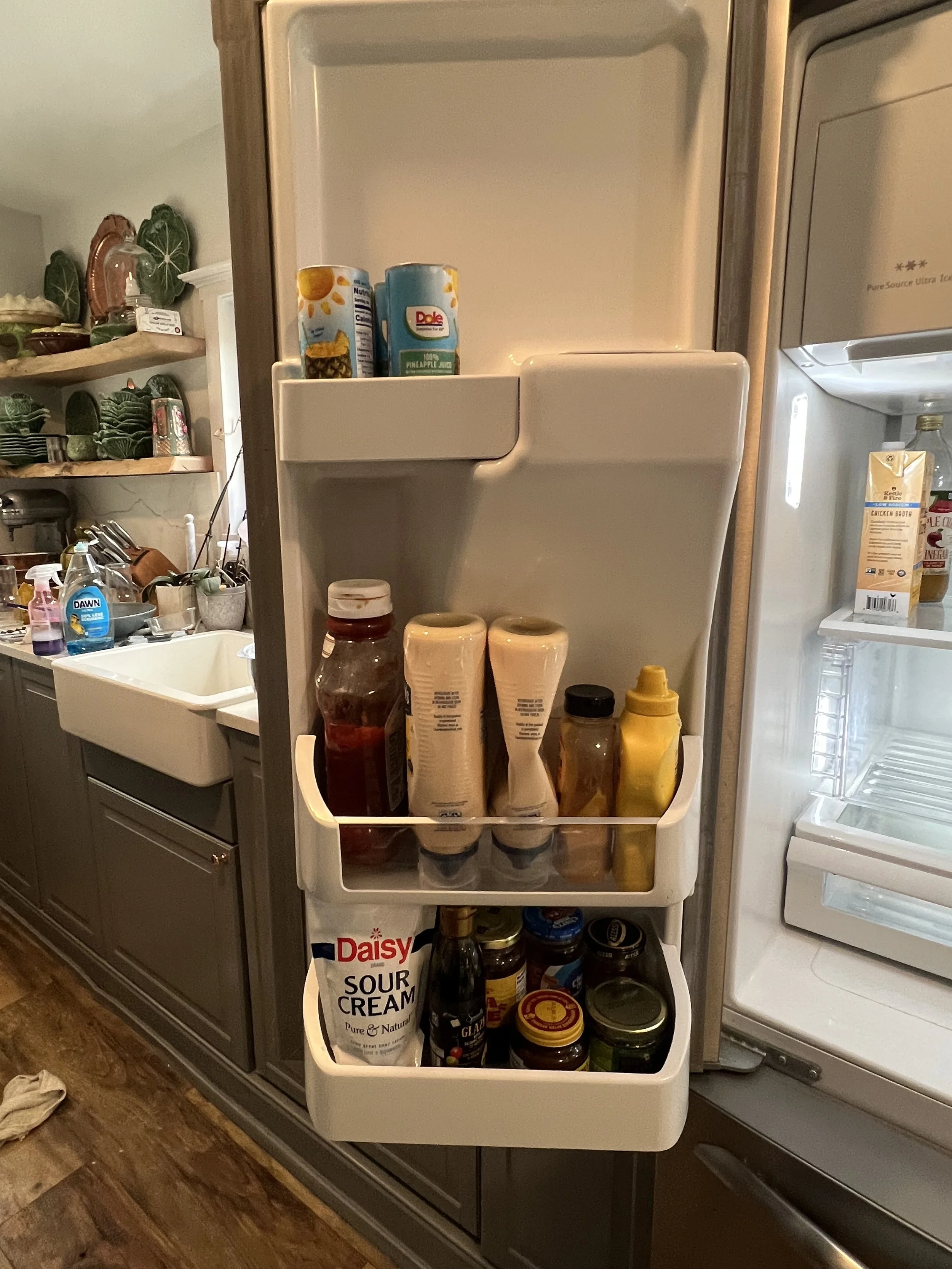 Open refrigerator door showing condiments, sauces, and jars on the shelves inside.