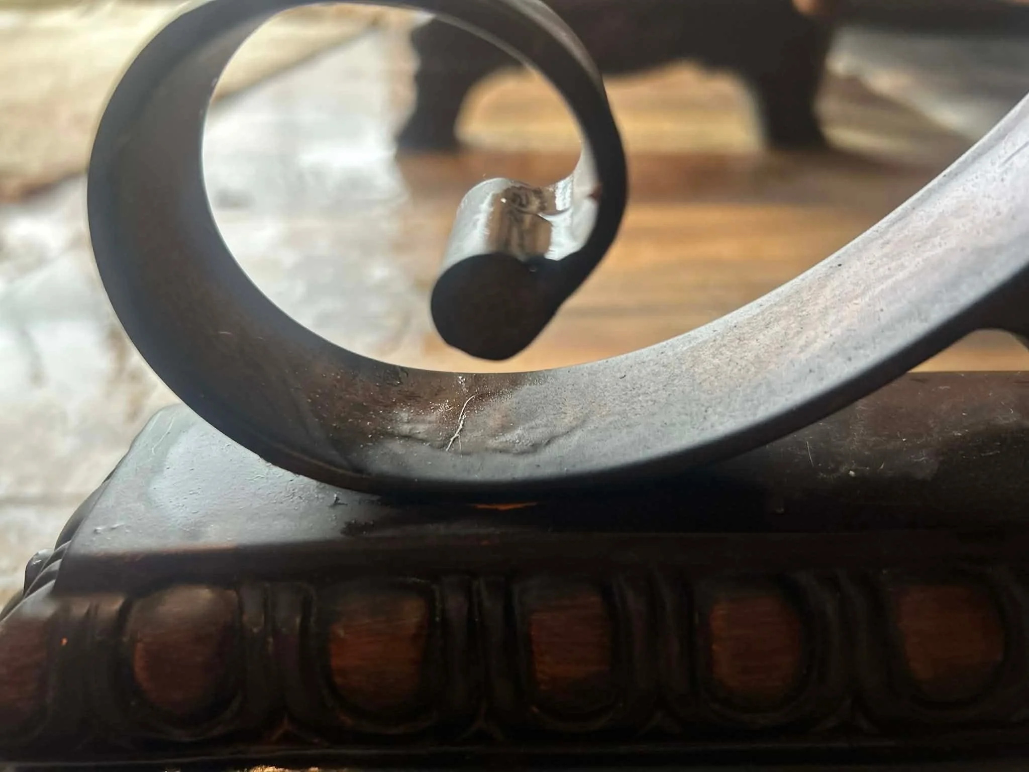Close-up of a shuriken (ninja star) on a carved wooden stand with a blurred background.