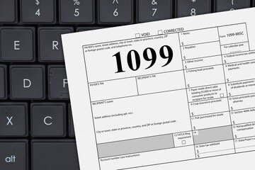 Close-up of a paper document labeled '1099-MISC' on a computer keyboard. BUSINESS TAX RETURN